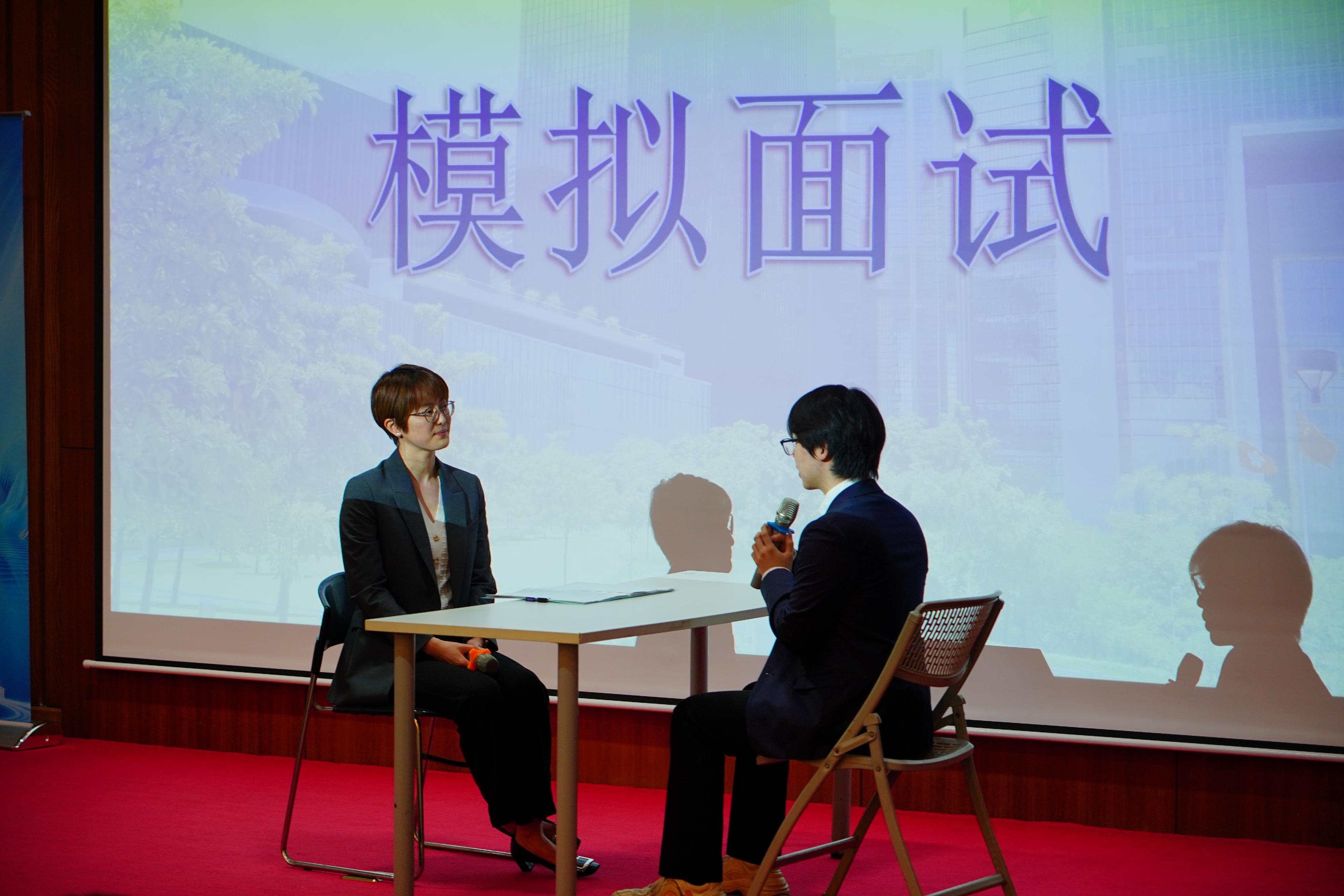 The Civil Service Bureau (CSB), together with representatives from the Civil Aviation Department, the Home Affairs Department and the Digital Policy Office, are visiting Guangzhou and Wuhan to conduct career talks at Sun Yat-sen University, Jinan University, Wuhan University and Huazhong University of Science and Technology for four consecutive days starting today (May 27), to provide Hong Kong students studying on the Mainland with information on various positions in the Hong Kong Special Administrative Region Government. Photo shows Career Development Manager of the General Grades Office of the CSB Miss Winmy Leung (left) conducting a mock interview for the Executive Officer Grade with a Hong Kong student at the career talk at Sun Yat-sen University today to let the student experience and other students to observe the interview process.