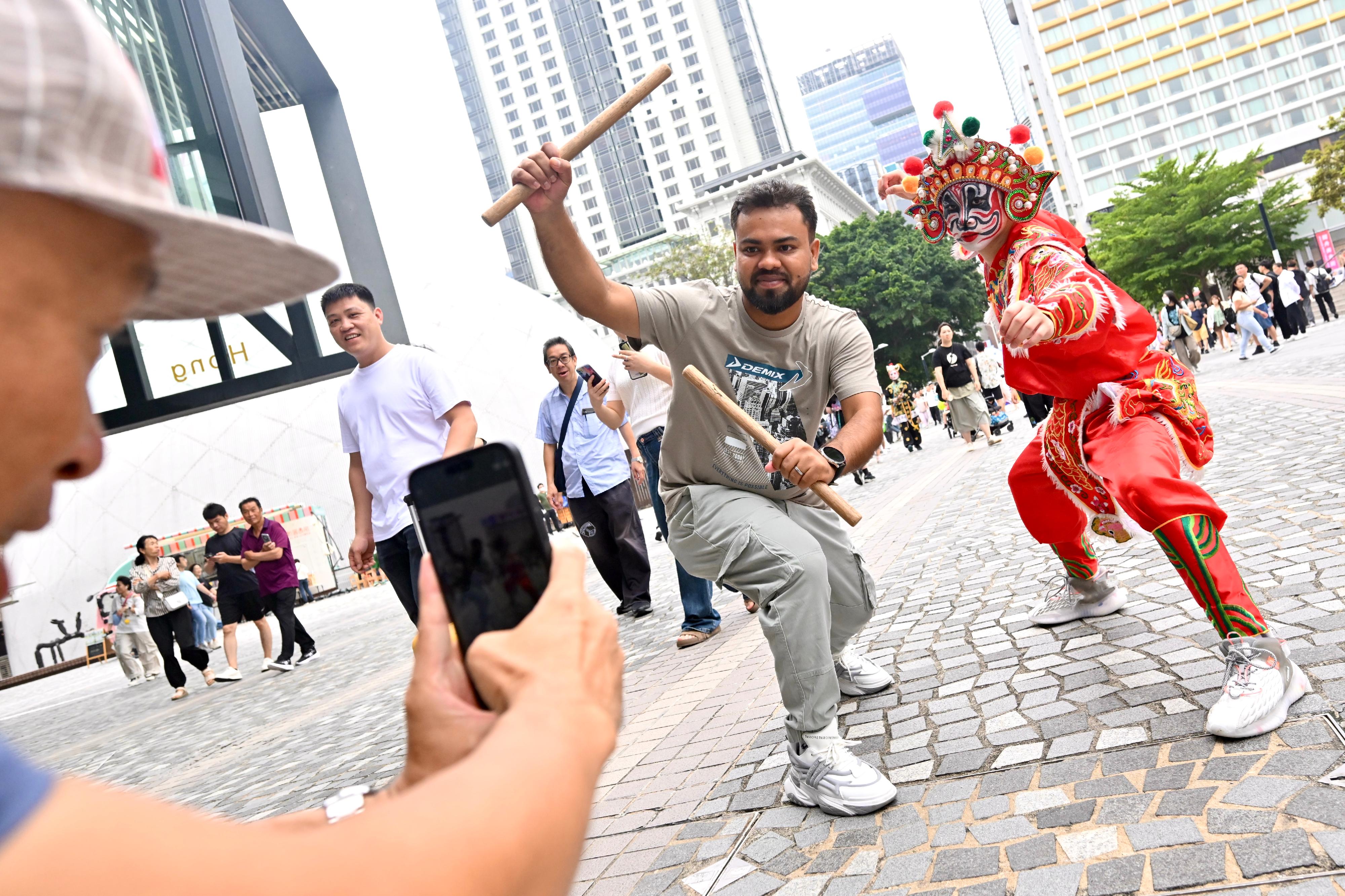 The Intangible Cultural Heritage Office is organising an Intangible Cultural Heritage Carnival today and tomorrow (May 31 to June 1) at the Hong Kong Cultural Centre Piazza. Photo shows a performer of Engor (Dance of Heroes) with a tourist.