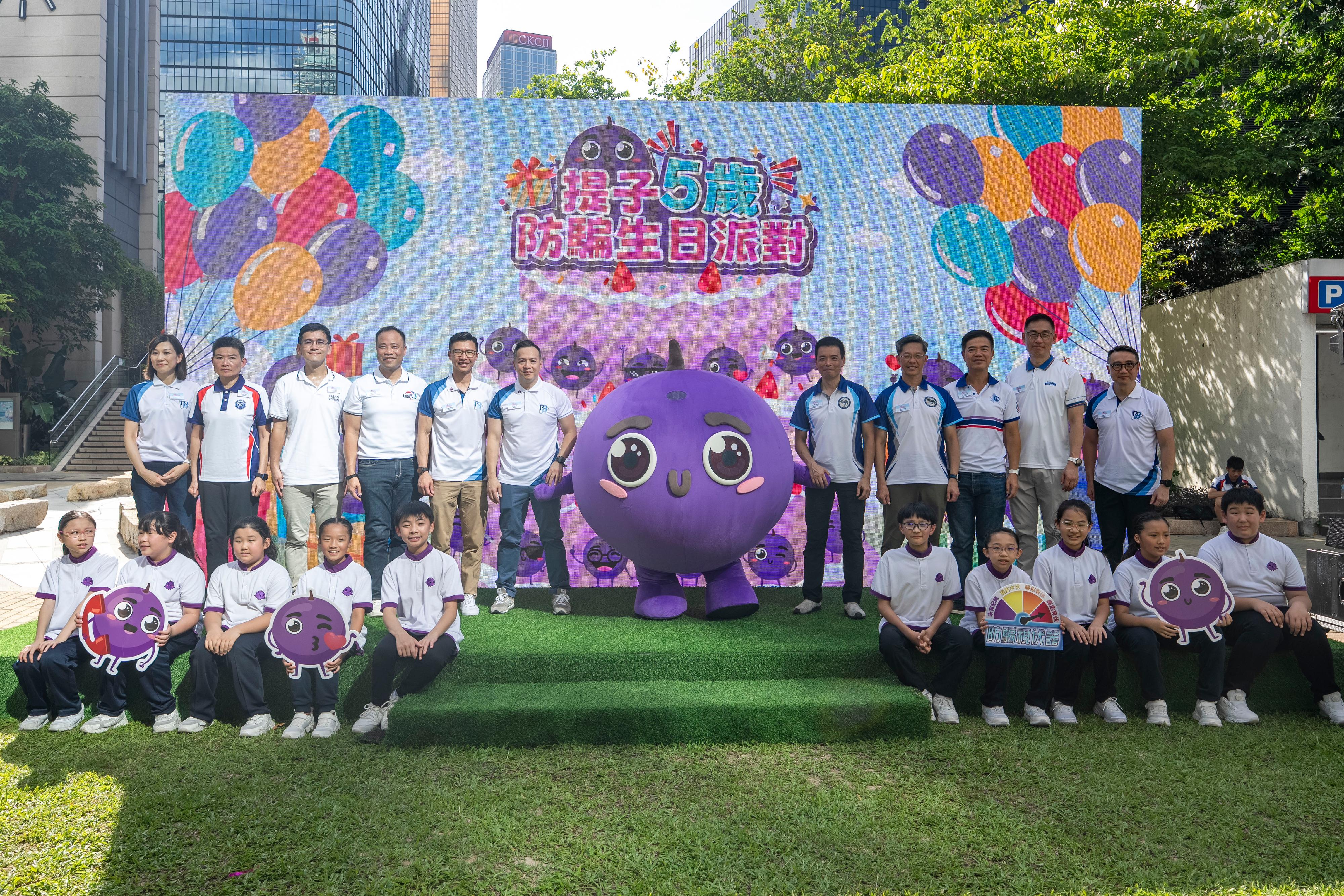 The Hong Kong Police Force organises the "The Little Grape’s 5th Anti-Scam Birthday Party" at the Harcourt Garden in Admiralty today (June 8). Photo shows the Commissioner of Police, Mr Chow Yat-ming (back row, sixth left); the Acting Assistant Commissioner of Police (Public Relations), Mr Leung Chung-man (back row, fifth left), other guests and participants taking a group photo with “The Little Grape” mascot.