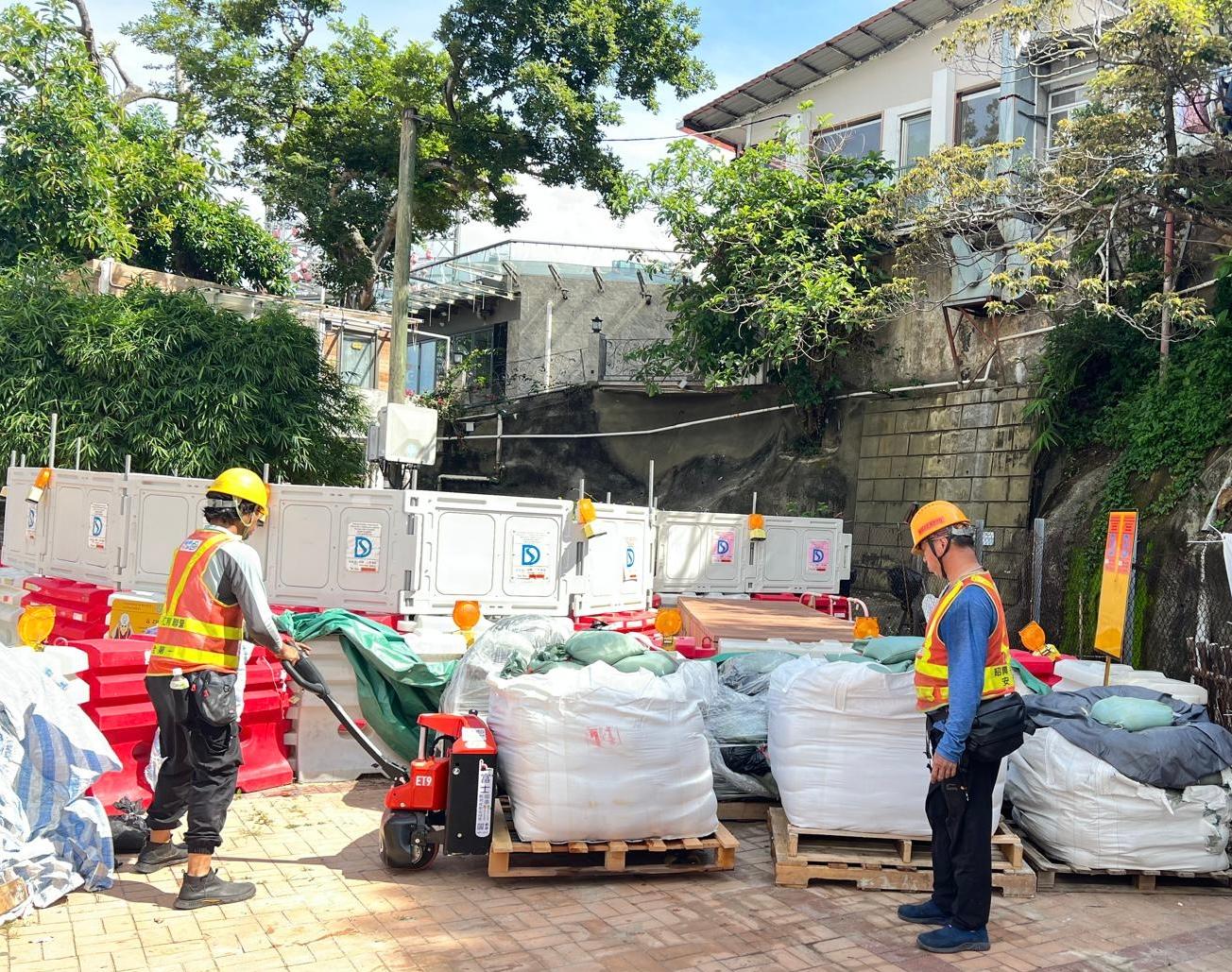 Officers of the Drainage Services Department inspected locations that had been hit by severe flooding in the past on June 11 to learn about the flood prevention measures implemented by the department. Photo shows DSD staff providing sandbags for residents at Lei Yue Mun.