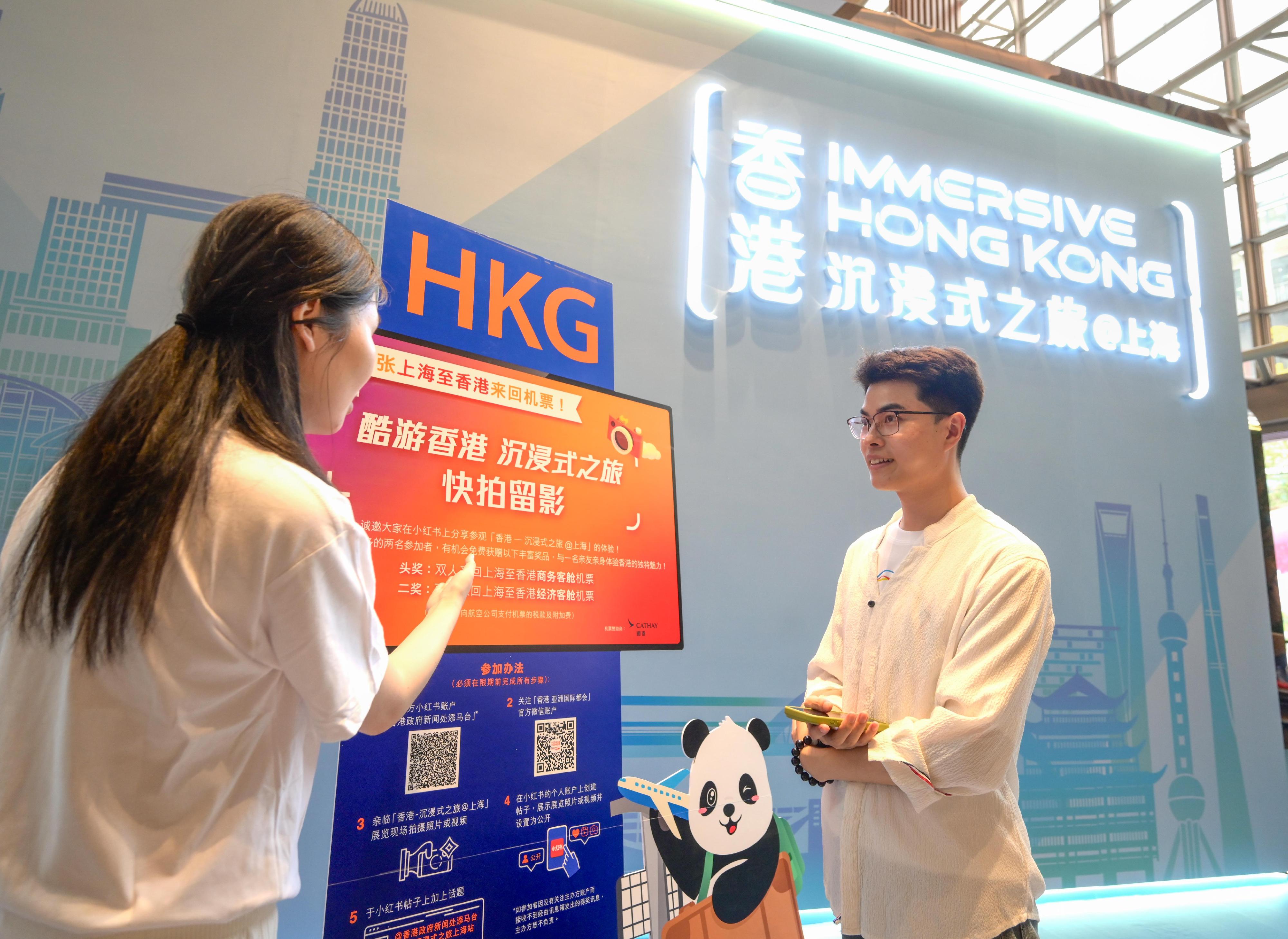 The "Immersive Hong Kong" roving exhibition, which showcases the charm and vibrancy of Hong Kong through interactive art technology, opened in Shanghai today (June 19). The exhibition invites visitors from Shanghai and the Yangtze River Delta to explore the unique opportunities and potential for tourism, education, business and investment in Hong Kong. An interactive game, "Snap a cool shot @Immersive Hong Kong", is taking place at the exhibition, with round-trip air tickets sponsored by Cathay Pacific as prizes. Photo shows a visitor learning about the information of the game.