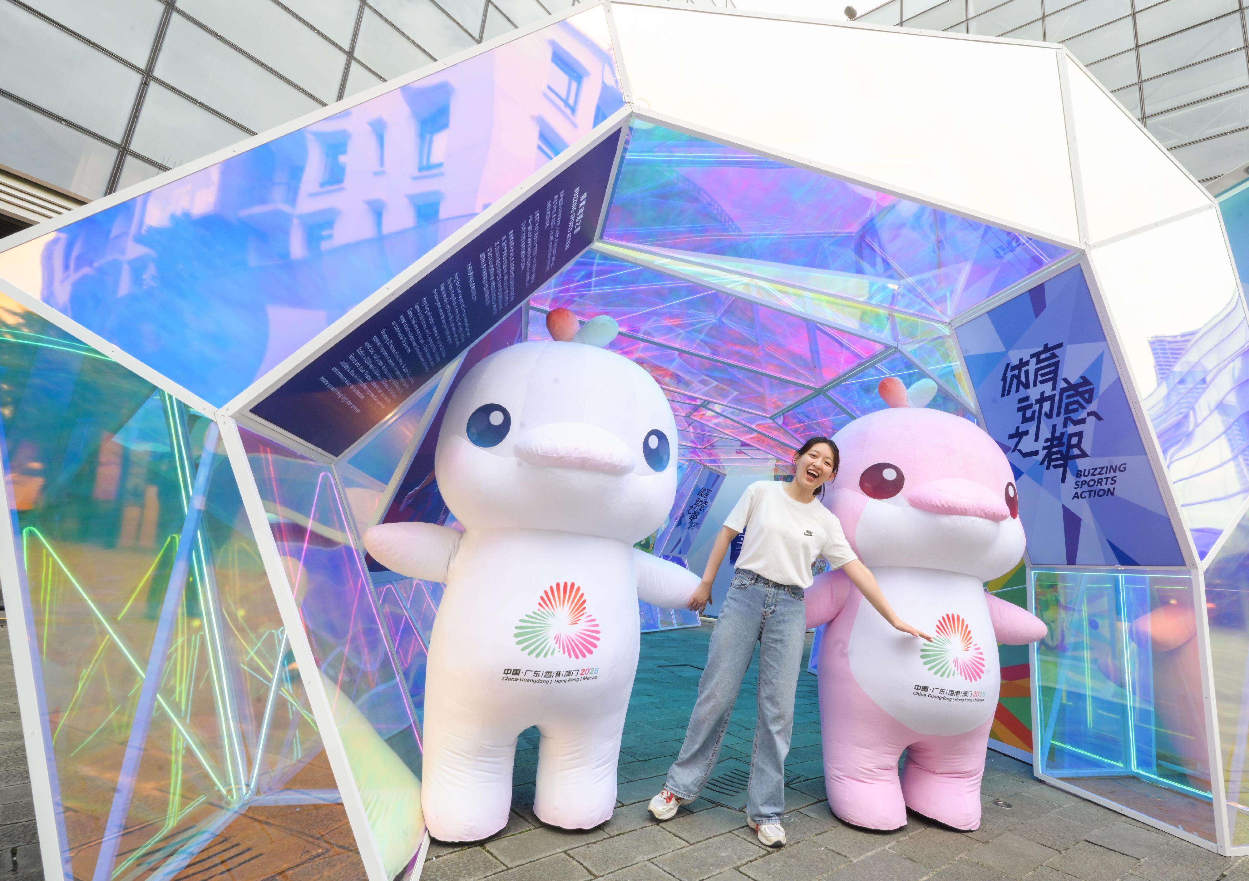 The "Immersive Hong Kong" roving exhibition, which showcases the charm and vibrancy of Hong Kong through interactive art technology, opened in Shanghai today (June 19). The exhibition invites visitors from Shanghai and the Yangtze River Delta to explore the unique opportunities and potential for tourism, education, business and investment in Hong Kong. Photo shows a visitor taking a photo with the mascots for the 15th National Games.
