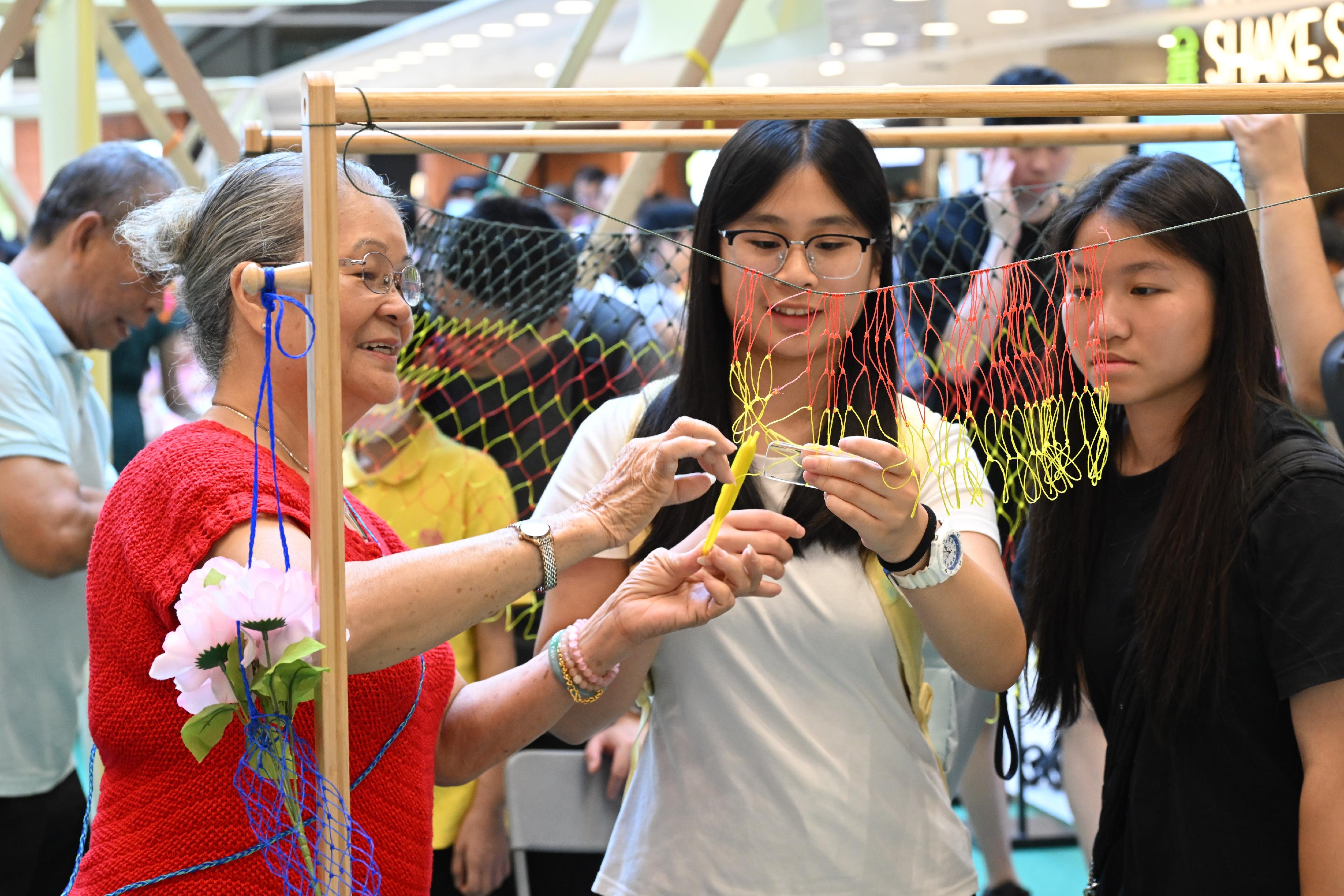 The "Encountering Chinese Culture" Carnival of the Chinese Culture Festival 2025 was held today (June 22) in Sha Tin. Photo shows members of the public experiencing the fishing net plaiting technique at the interactive booth. 