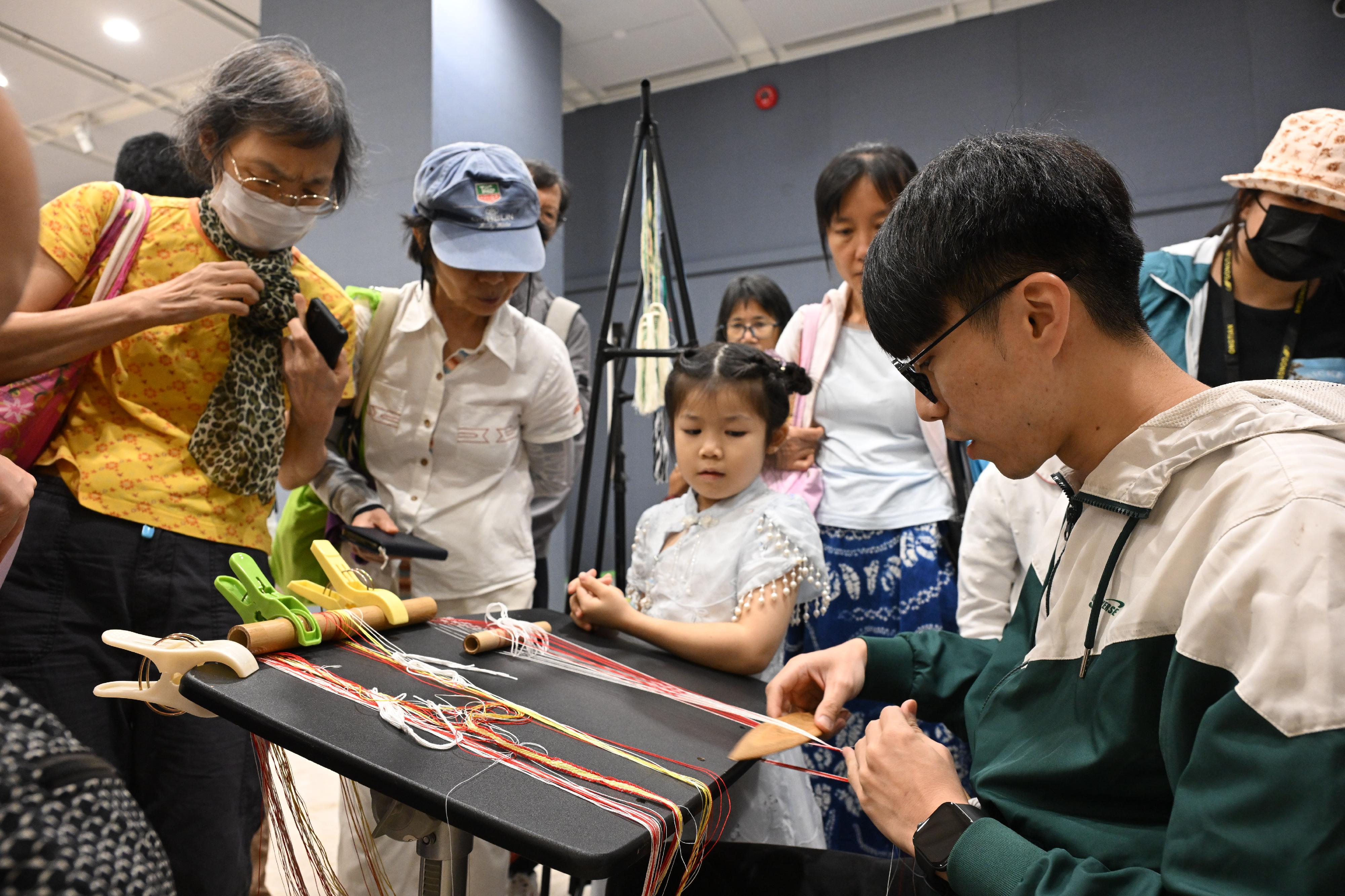 The "Encountering Chinese Culture" Carnival of the Chinese Culture Festival 2025 was held today (June 22) in Sha Tin. Photo shows members of the public experiencing the patterned band weaving technique at the interactive booth. 