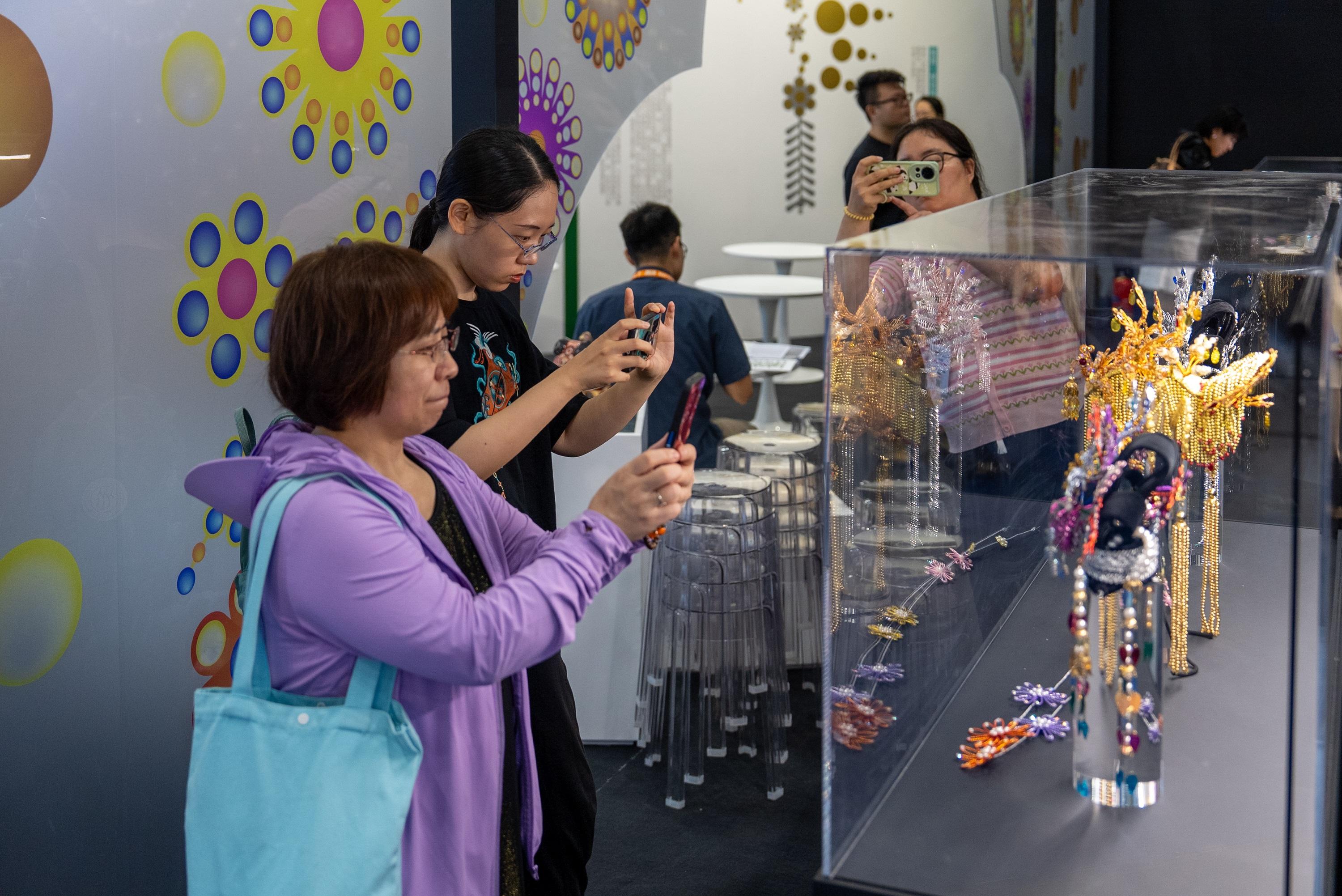 文化體育及旅遊局文創產業發展處（文創處）於六月十八日至二十二日率領業界參與第三十一屆北京國際圖書博覽會，並以「漫步香港：非遺與城市記憶」為主題主辦香港館。圖示觀眾參觀香港館主題展區內的非遺粵劇頭飾展品。
