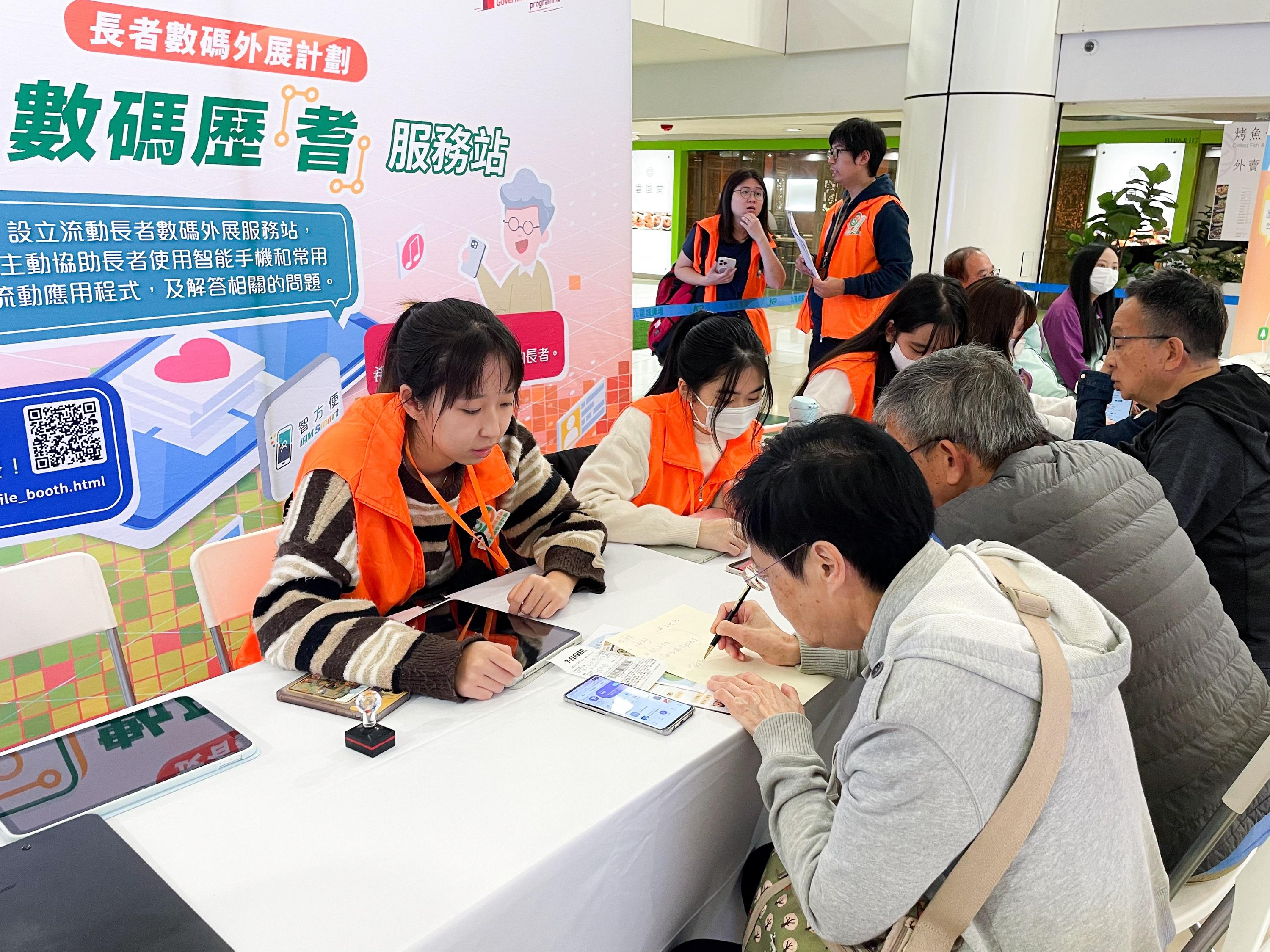 新一輪「友智識」長者數碼外展計劃的推行機構會在全港各區舉辦流動數碼服務站活動。圖示數字辦與上一輪計劃的推行機構設立的流動數碼服務站，解答長者查詢有關使用智能手機的問題。