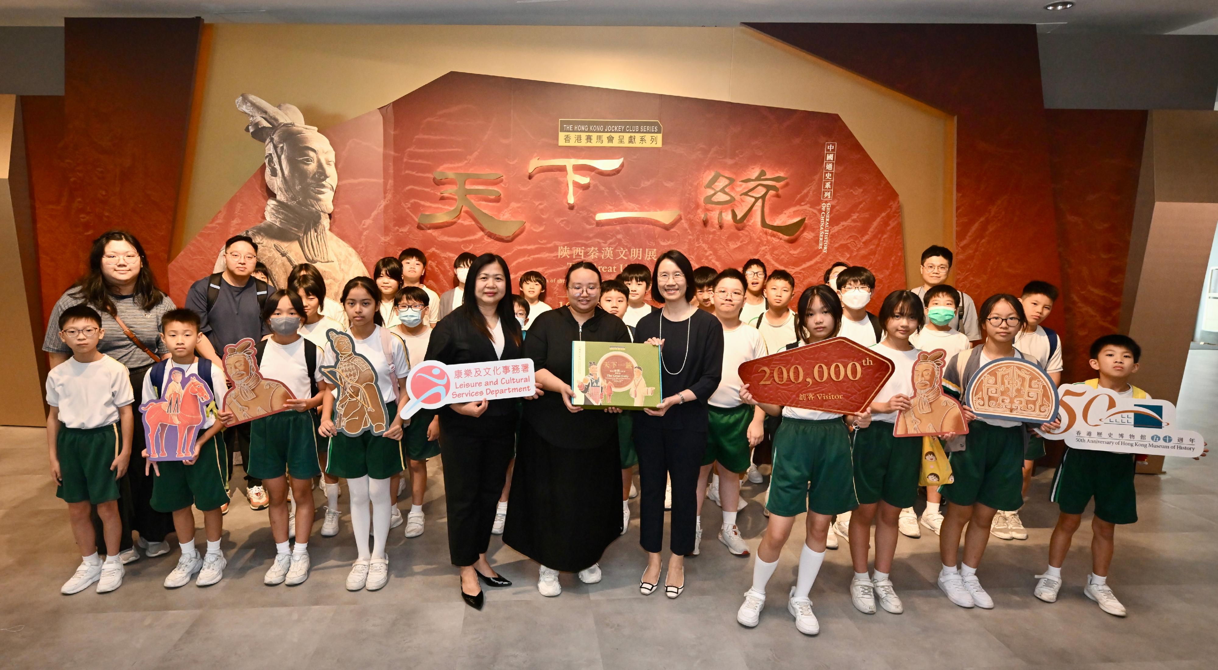 香港歷史博物館的「香港賽馬會呈獻系列：天下一統—陝西秦漢文明展」，自四月十六日開展以來，深受市民及旅客歡迎。展覽今日（六月三十日）迎來第二十萬名參觀者。圖示康樂及文化事務署署長陳詠雯（前排右五）和香港歷史博物館總館長何惠儀（前排左五），向第二十萬名訪客送上紀念品。