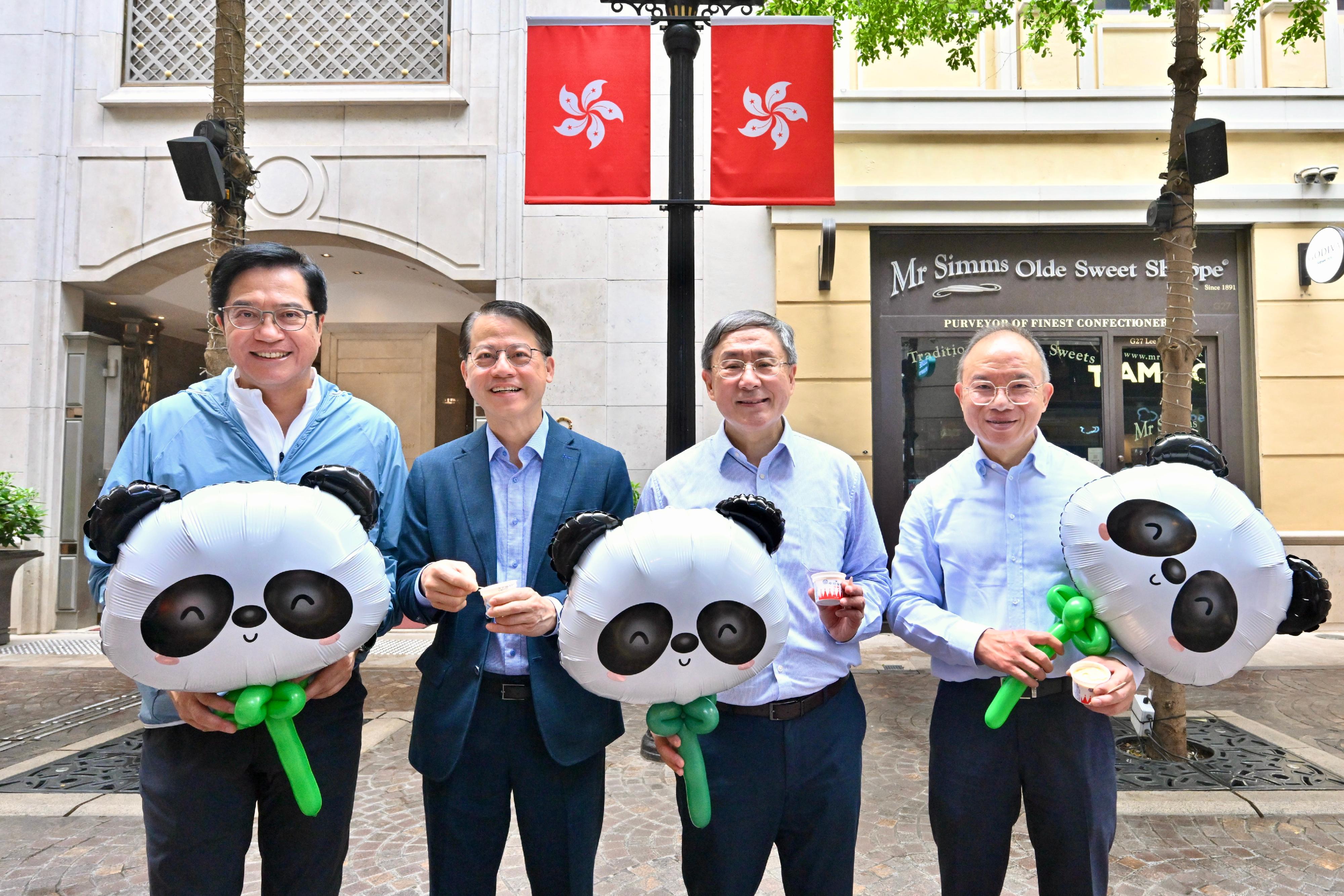 The Deputy Chief Secretary for Administration, Mr Cheuk Wing-hing (second right); the Deputy Financial Secretary, Mr Michael Wong (first left); and the Secretary for Constitutional and Mainland Affairs, Mr Erick Tsang Kwok-wai (first right), experience the festive atmosphere featuring free distributions of ice cream, popcorn and panda-shaped balloons at Lee Tung Avenue, Wan Chai today (July 1). Also present is the Associate Director of Sino Estates Management Limited, Mr Nelson Chiu (second left).
