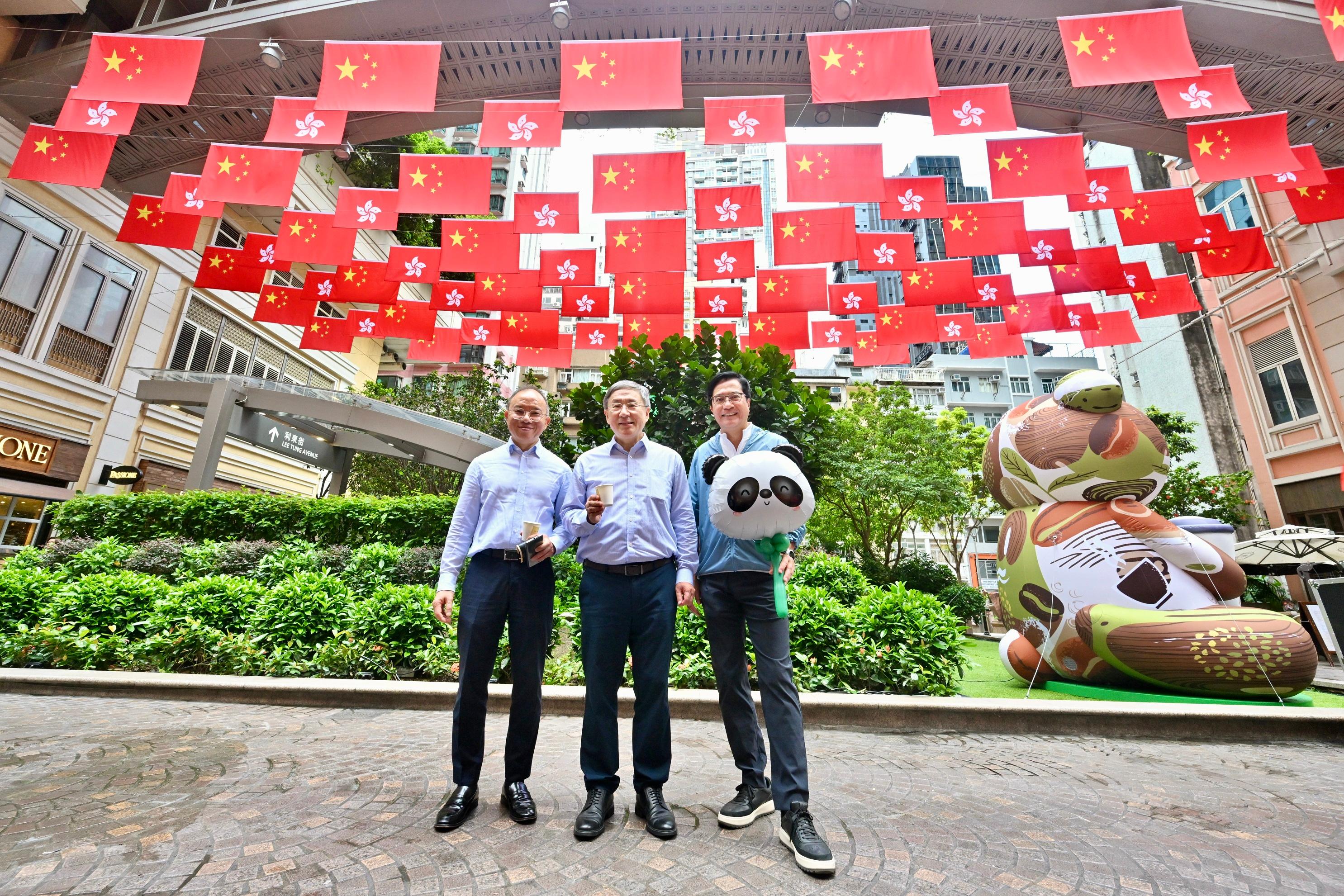 The Deputy Chief Secretary for Administration, Mr Cheuk Wing-hing (centre); the Deputy Financial Secretary, Mr Michael Wong (right); and the Secretary for Constitutional and Mainland Affairs, Mr Erick Tsang Kwok-wai (left), today (July 1) are pictured in a sea of red with national flags and HKSAR flags at Lee Tung Avenue in Wan Chai.
