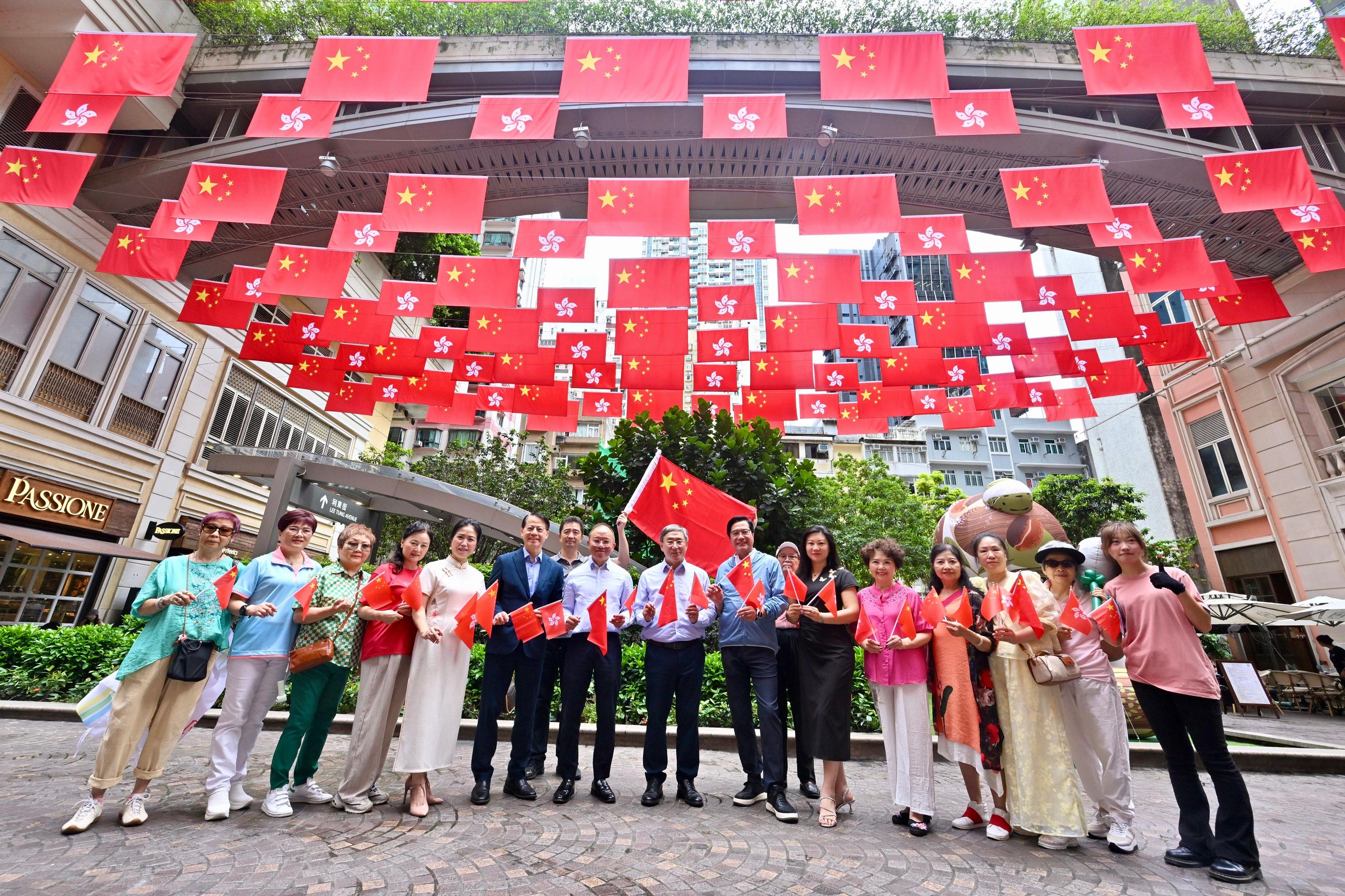 The Deputy Chief Secretary for Administration, Mr Cheuk Wing-hing (centre); the Deputy Financial Secretary, Mr Michael Wong (seventh right); and the Secretary for Constitutional and Mainland Affairs, Mr Erick Tsang Kwok-wai (seventh left), today (July 1) join a group photo with members of the public in a sea of red with national flags and HKSAR flags at Lee Tung Avenue in Wan Chai.