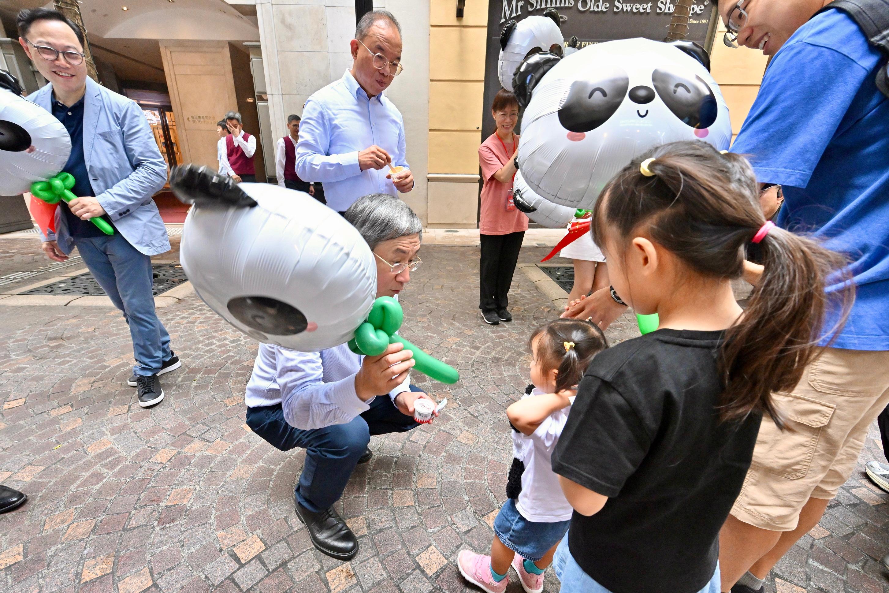 The Deputy Chief Secretary for Administration, Mr Cheuk Wing-hing, gives away ice cream and panda-shaped balloons to a little girl at Lee Tung Avenue in Wan Chai today (July 1).

