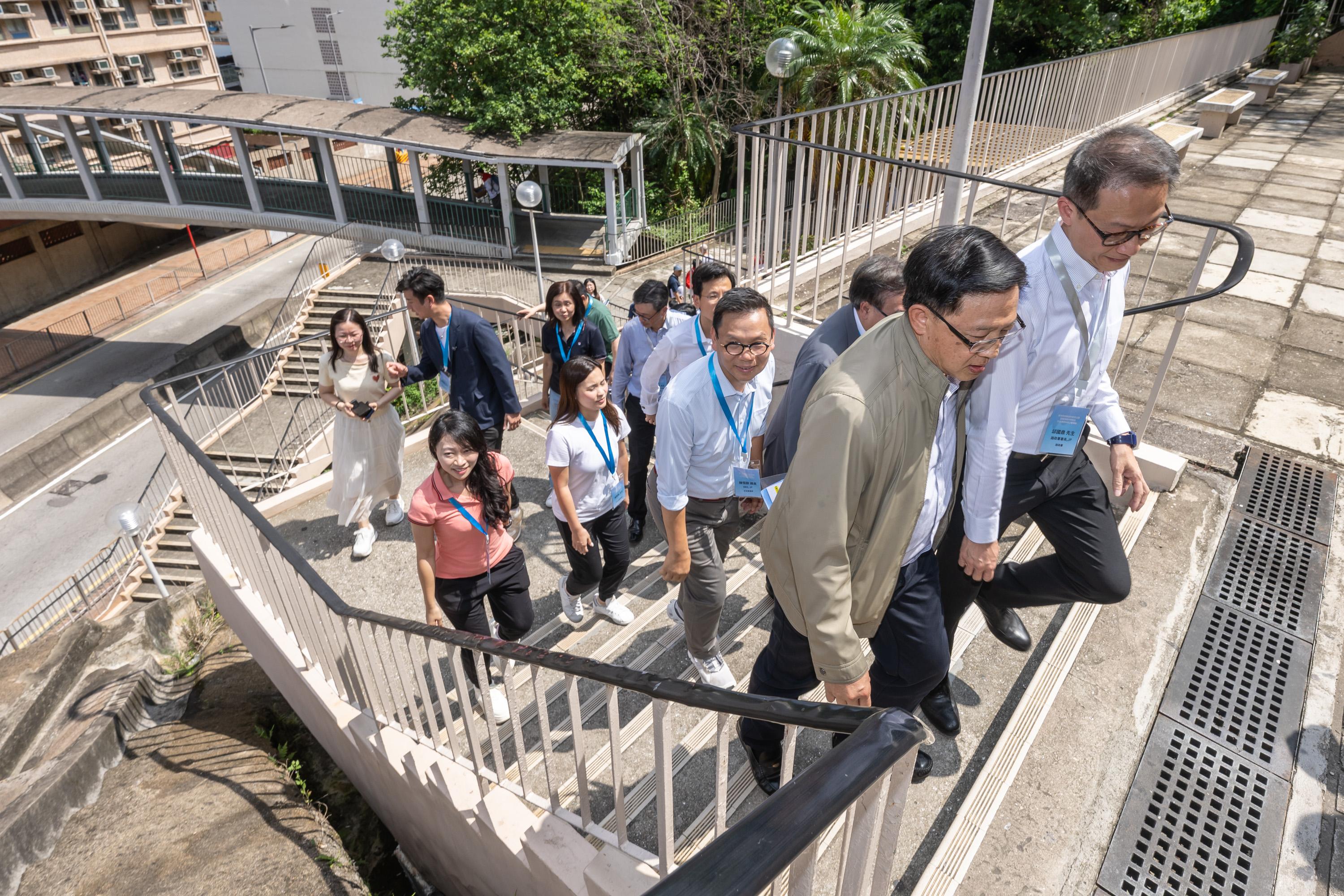 The Legislative Council (LegCo) Members and Kwai Tsing District Council members inspect the proposed lift and pedestrian walkway system between Lai King Hill Road and Lai Cho Road today (July 4) to follow up on the issue of enhancing barrier-free facilities in Kwai Tsing. Photo shows LegCo Members gaining first-hand experience about the condition of the existing staircase connecting the two locations.
