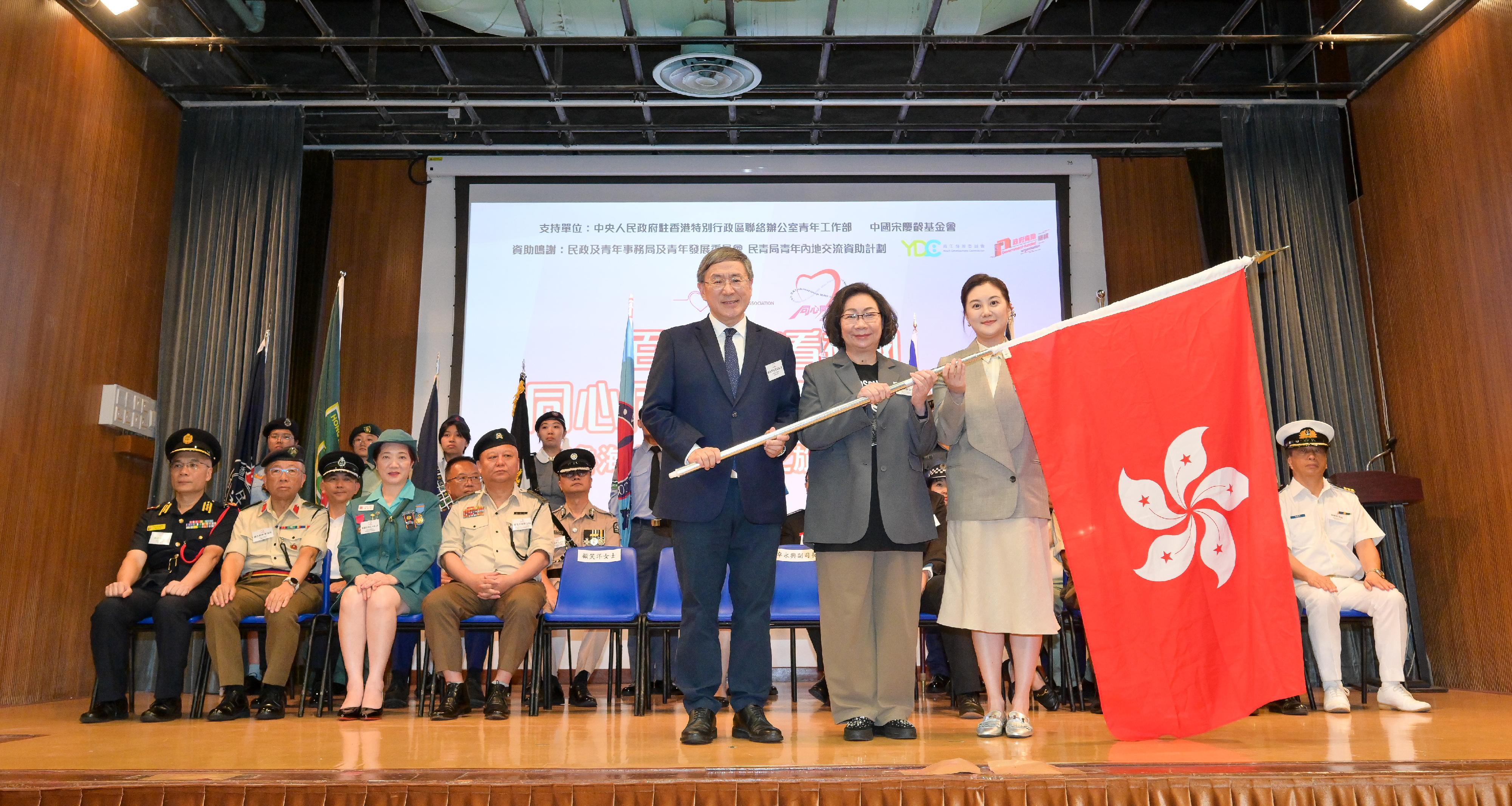 政務司副司長卓永興（左）今日（七月十一日）在醫療輔助隊總部舉行的同心同根萬里行2025授旗禮上，頒授區旗予同心同根會創會會長、同心同根萬里行2025活動召集人暨團長梁唐青儀（中）和同心同根萬里行2025榮譽團長顧笑洋（右）。