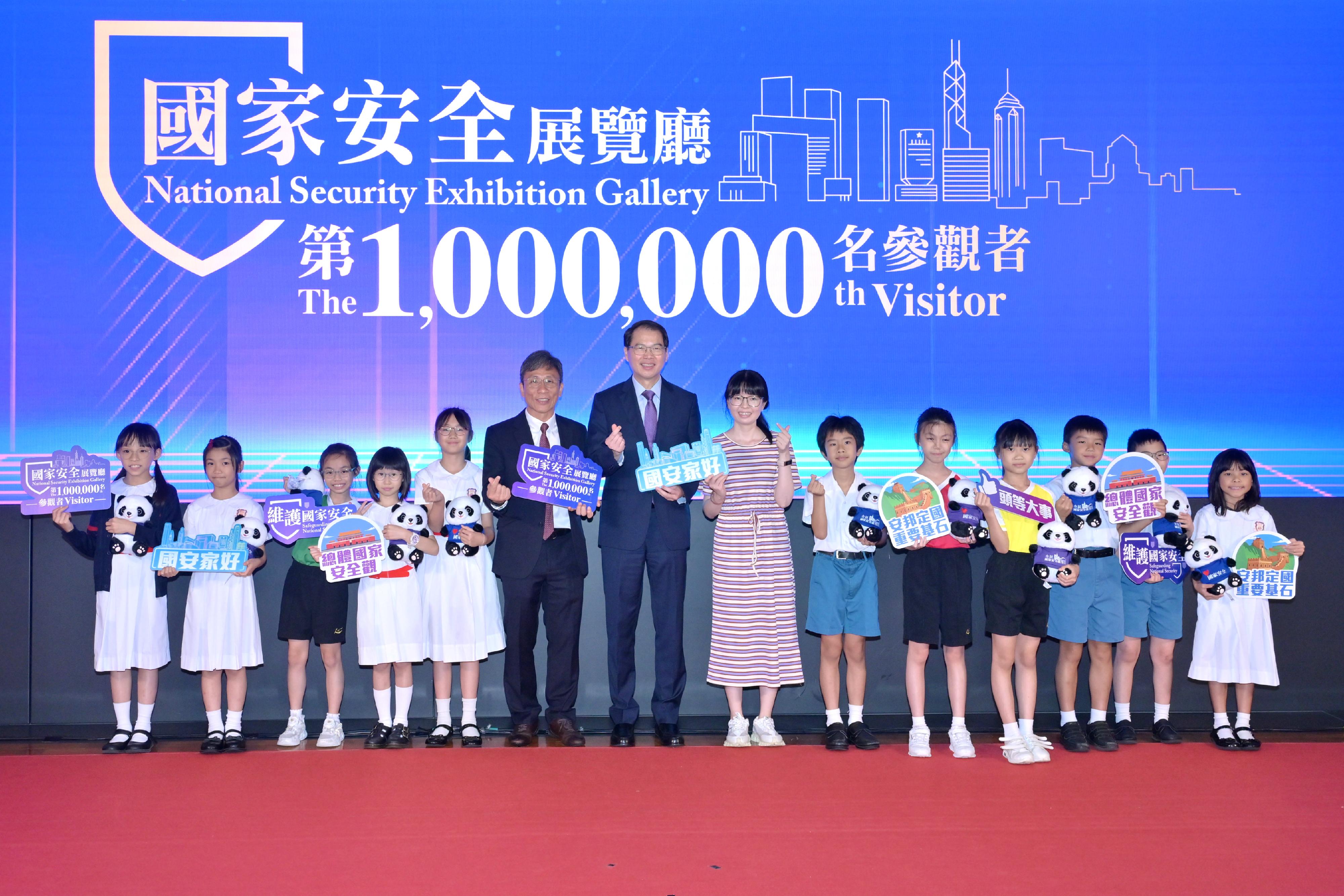 Secretary General of the Committee for Safeguarding National Security , Mr Au Chi-kwong (seventh left), is pictured with the one-millionth visitor to the National Security Exhibition Gallery, students from the Po Leung Kuk Luk Hing Too Primary School.