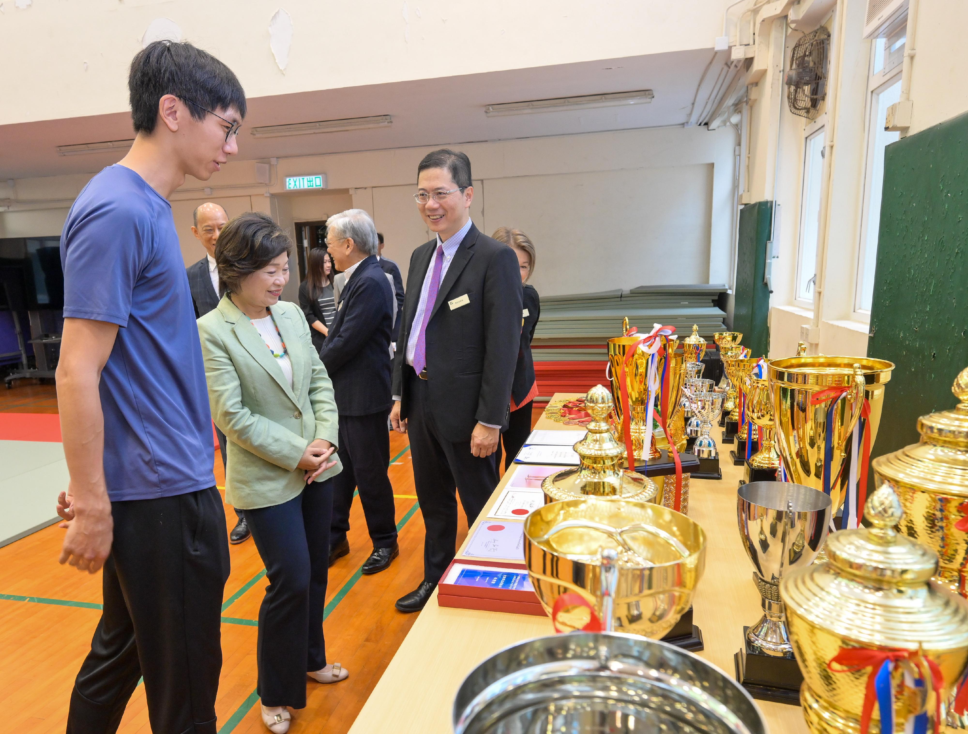 教育局局長蔡若蓮博士今日（七月十六日）到訪王肇枝中學，勉勵應屆香港中學文憑考試考生。圖示學校代表向蔡若蓮博士（左二）介紹學生在不同運動比賽中得到的獎項。