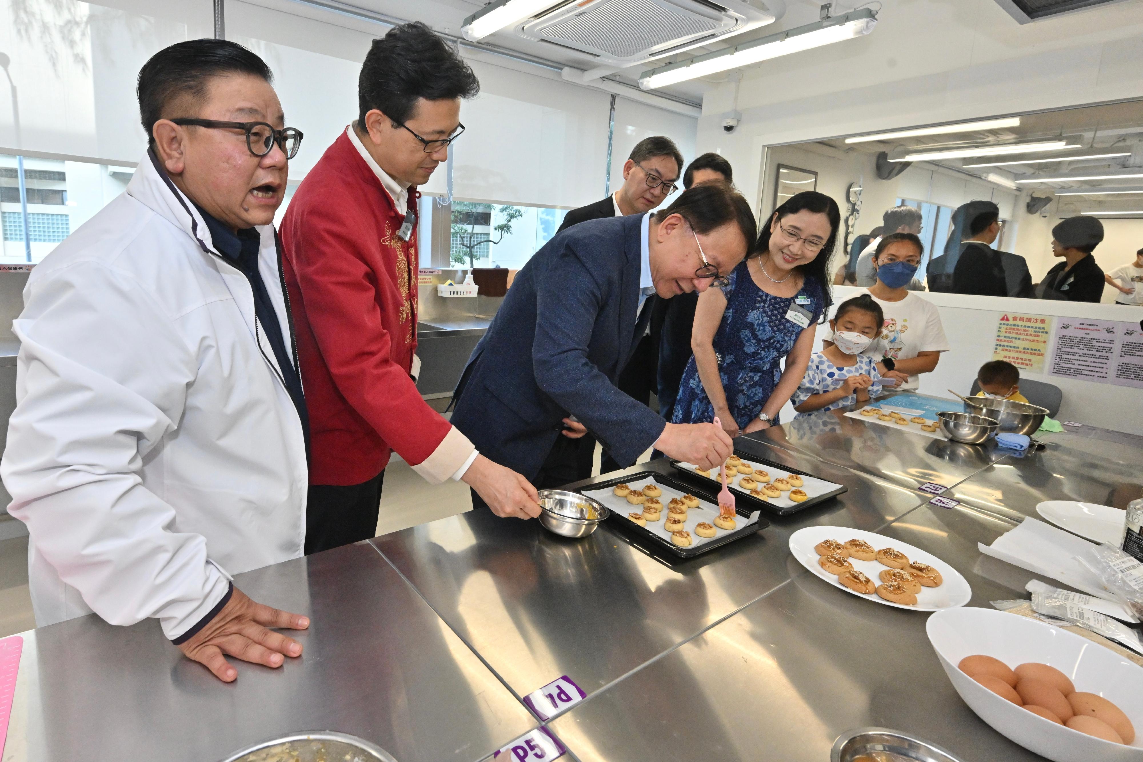 政務司司長陳國基今日（七月十七日）主持太子社區客廳開幕典禮。勞工及福利局局長孫玉菡、恒基兆業地產有限公司執行董事黃浩明、勞工及福利局常任秘書長劉焱、社會福利署署長杜永恒和樂群社會服務處執行委員會主席吳秋北博士亦一同主禮。圖示陳國基（左三）在備餐工房製作合桃酥。