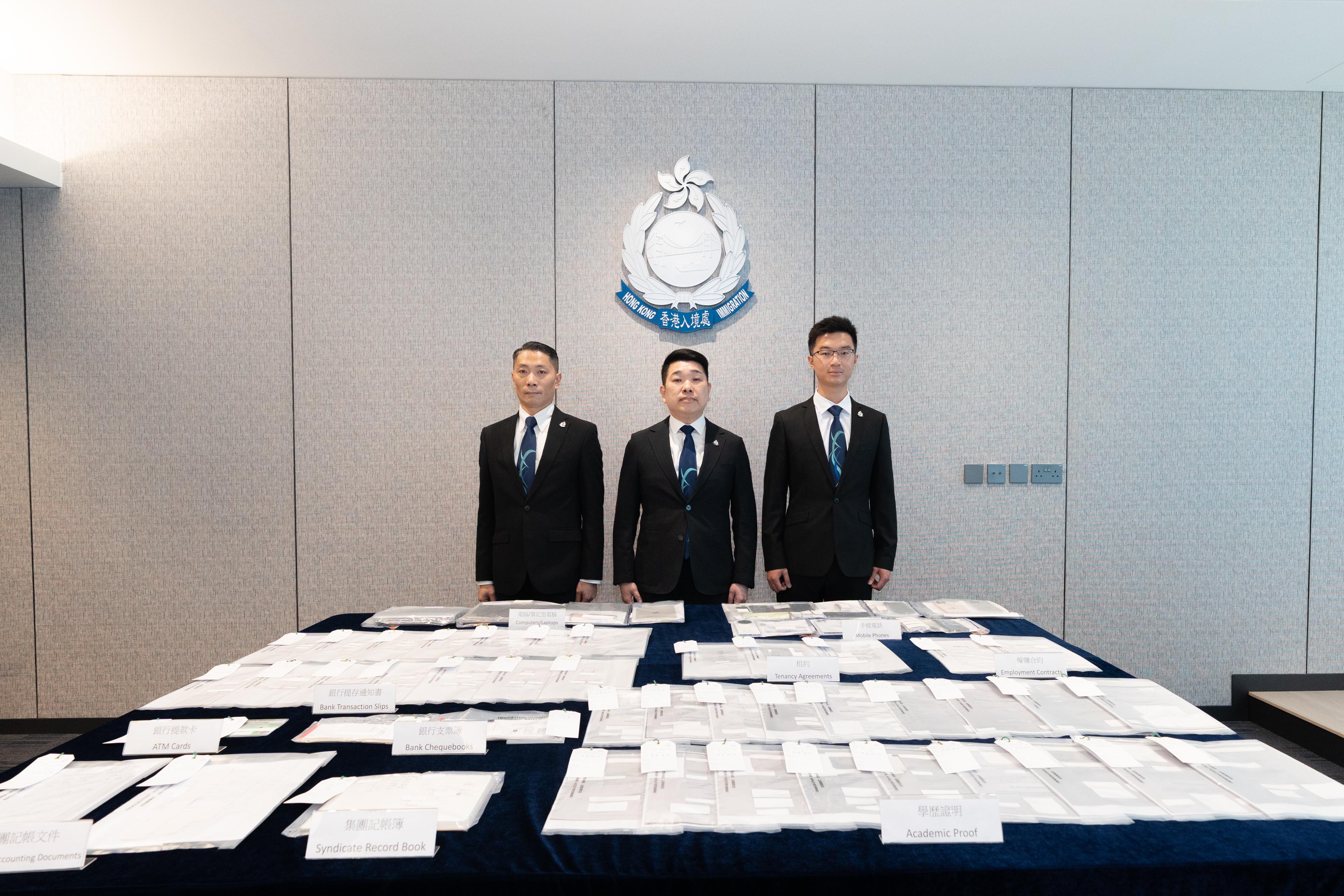 入境處瓦解一個利用虛假文書騙取高端人才通行證計劃入境許可的跨境犯罪集團。圖示助理首席入境事務主任（調查）許志堅（中）及調查人員今日（七月二十三日）在新聞發布會展示行動中部分檢獲的證物。
