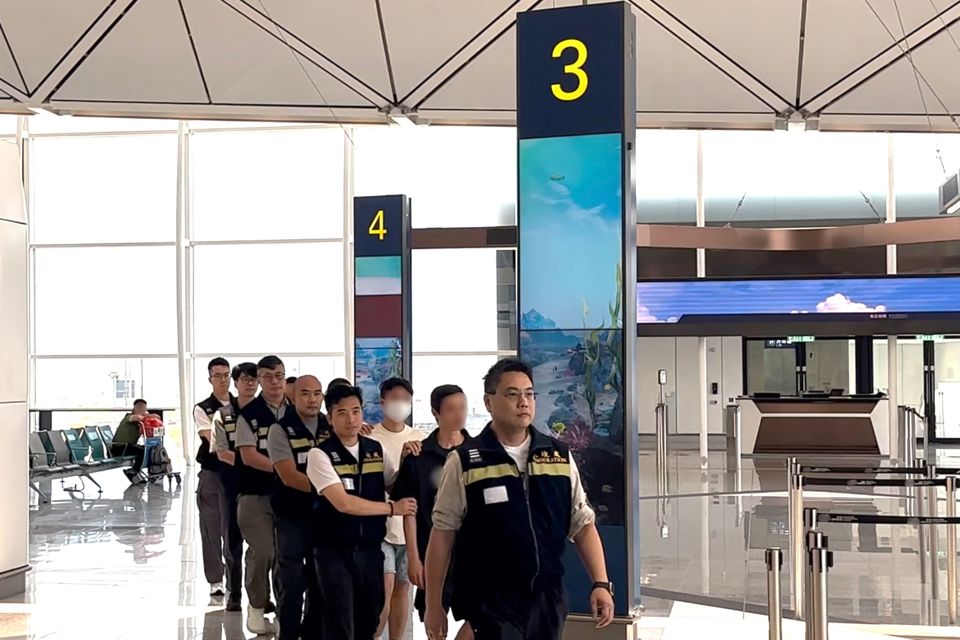 The Immigration Department (ImmD) carried out a repatriation operation today (July 25). A total of 17 Vietnamese illegal immigrants and overstayers were repatriated to Vietnam. Photo shows removees being escorted by ImmD officers to depart from Hong Kong.