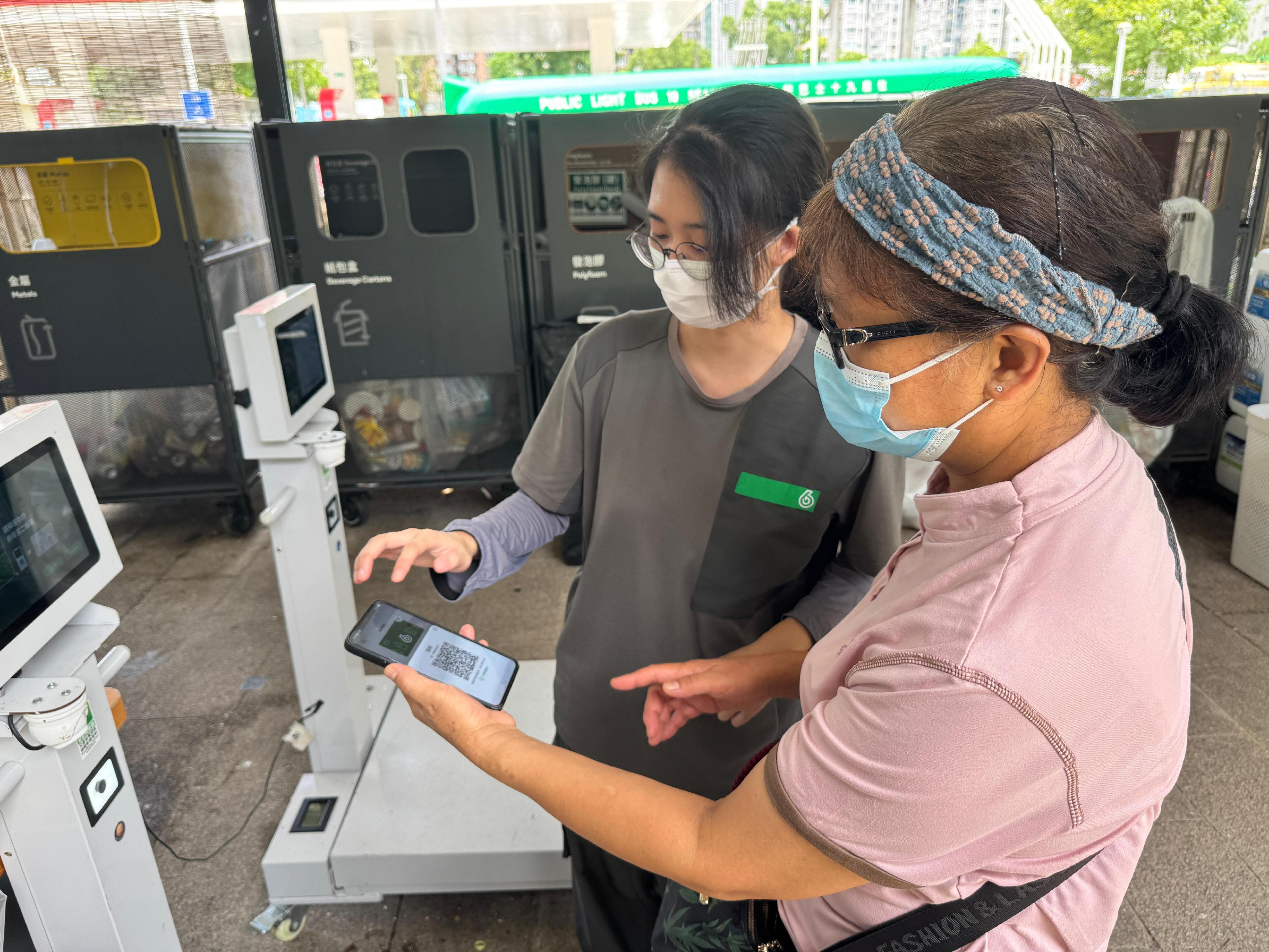 The Environmental Protection Department announced today (July 24) that the GREEN$ Electronic Participation Incentive Scheme (GREEN$ ePIS) will be fully digitised on April 1, 2026. Photo shows a staff of GREEN@COMMUNITY assisting the public in using GREEN$ mobile app to recycle.