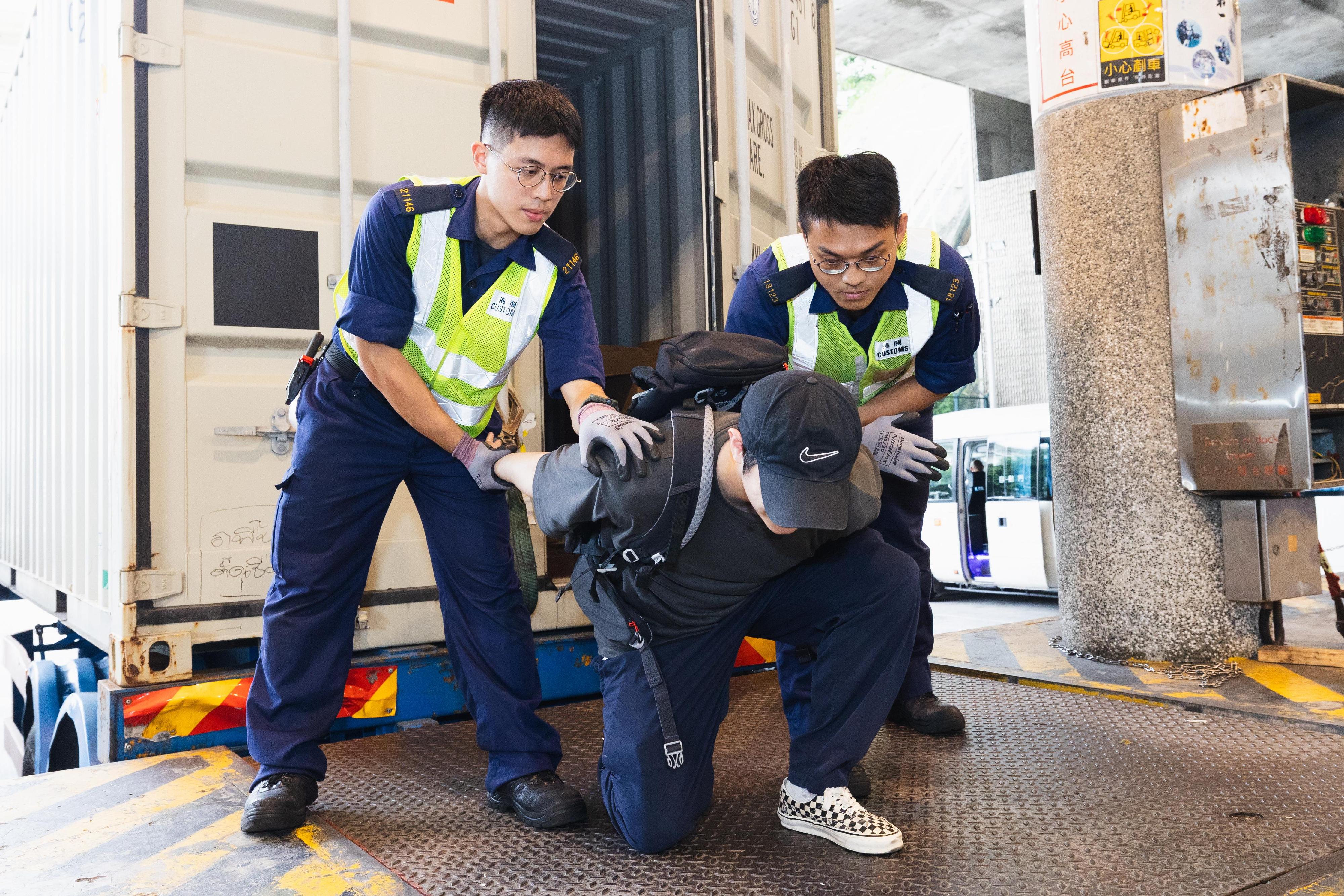 Hong Kong Customs, the Immigration Department and the Fire Services Department conducted a joint counter-terrorism intelligence handling and hazardous material incident exercise codenamed "TREADING SEA" this afternoon (July 28) at the Tsing Yi Cargo Examination Compound. Photo shows Customs officers subduing an illegal immigrant suspected of being connected to a terrorist organisation.