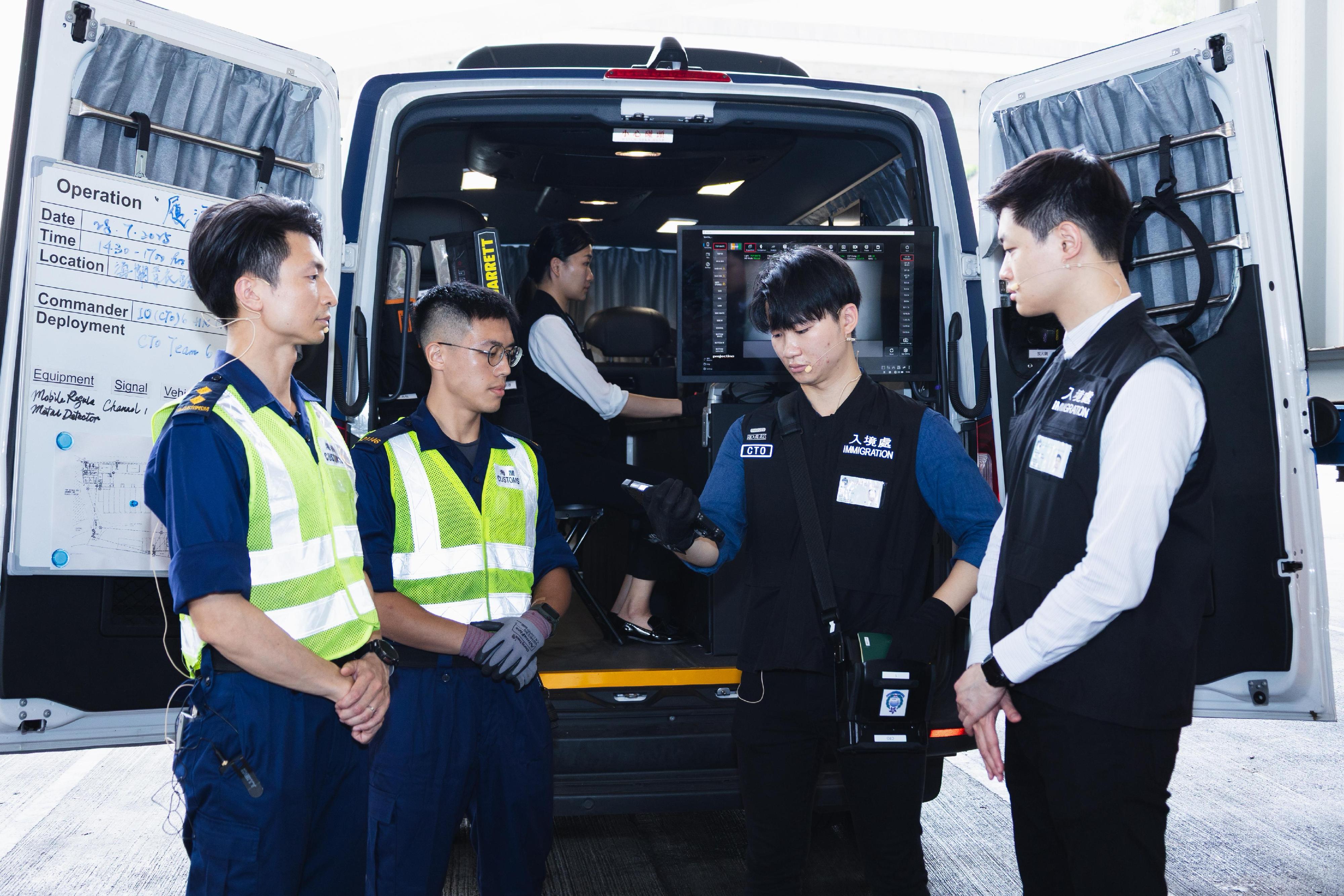 Hong Kong Customs, the Immigration Department (ImmD) and the Fire Services Department conducted a joint counter-terrorism intelligence handling and hazardous material incident exercise codenamed "TREADING SEA" this afternoon (July 28) at the Tsing Yi Cargo Examination Compound. Photo shows ImmD officers making use of the Mobile Identification Tactical Unit equipped with sophisticated document examination devices to verify the authenticity of the travel documents held by the illegal immigrant.
