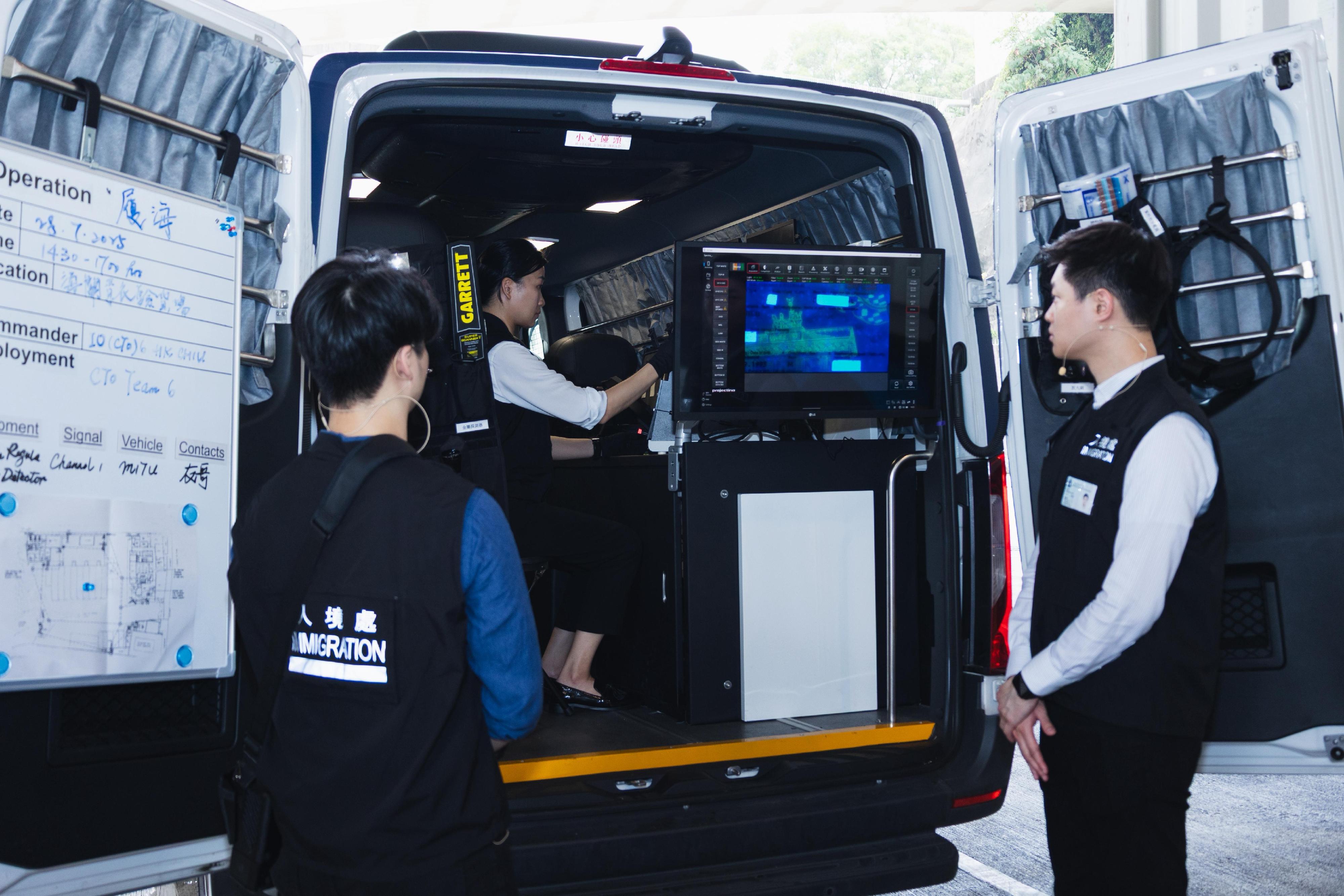 Hong Kong Customs, the Immigration Department (ImmD) and the Fire Services Department conducted a joint counter-terrorism intelligence handling and hazardous material incident exercise codenamed "TREADING SEA" this afternoon (July 28) at the Tsing Yi Cargo Examination Compound. Photo shows ImmD officers making use of the Mobile Identification Tactical Unit equipped with sophisticated document examination devices to verify the authenticity of the travel documents held by the illegal immigrant.