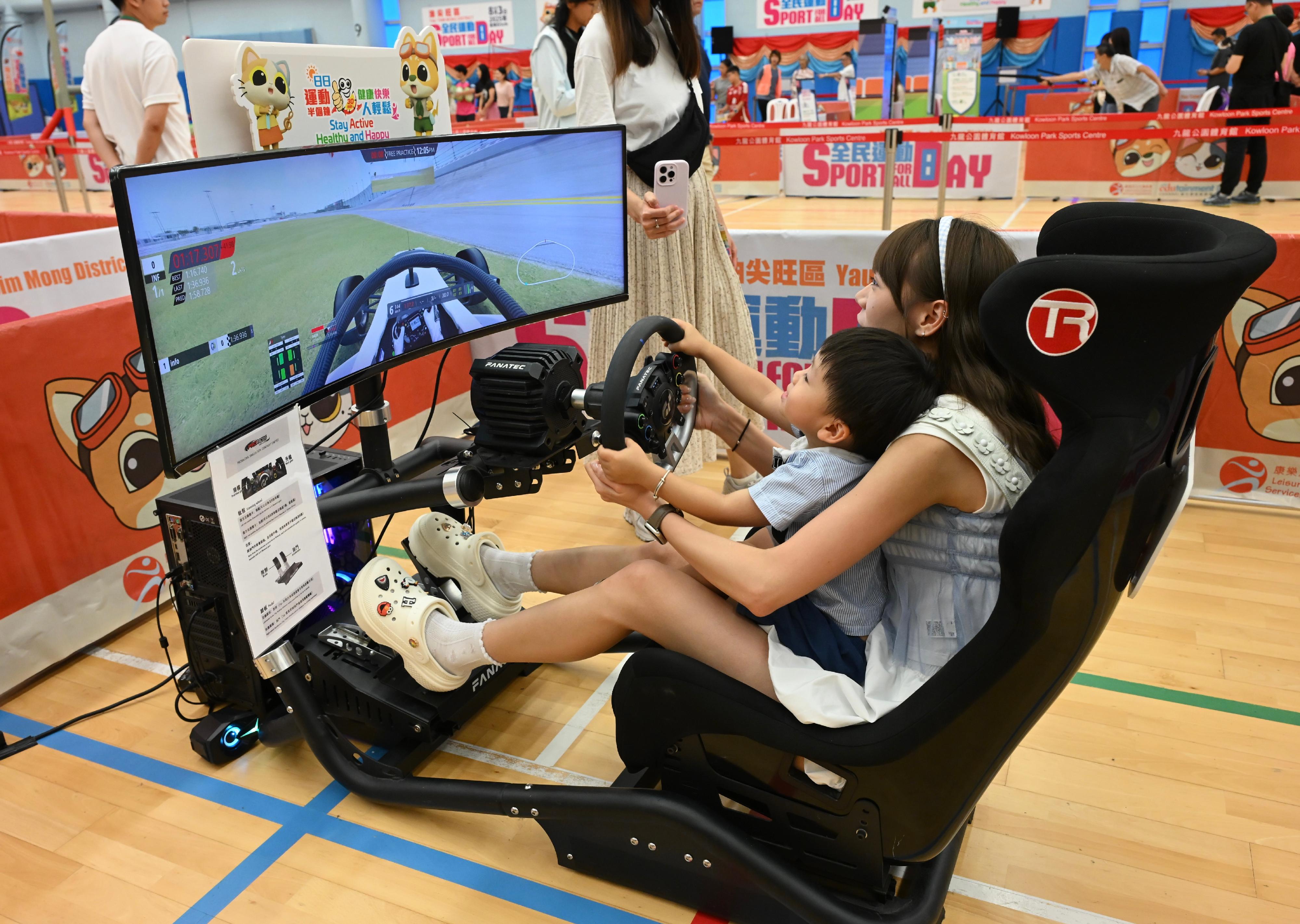 The Sport For All Day 2025 was held by the Leisure and Cultural Services Department today (August 3) with free recreation and sports programmes at designated sports centres in 18 districts for the public to join. Photo shows members of the public taking part in the virtual karting game. 