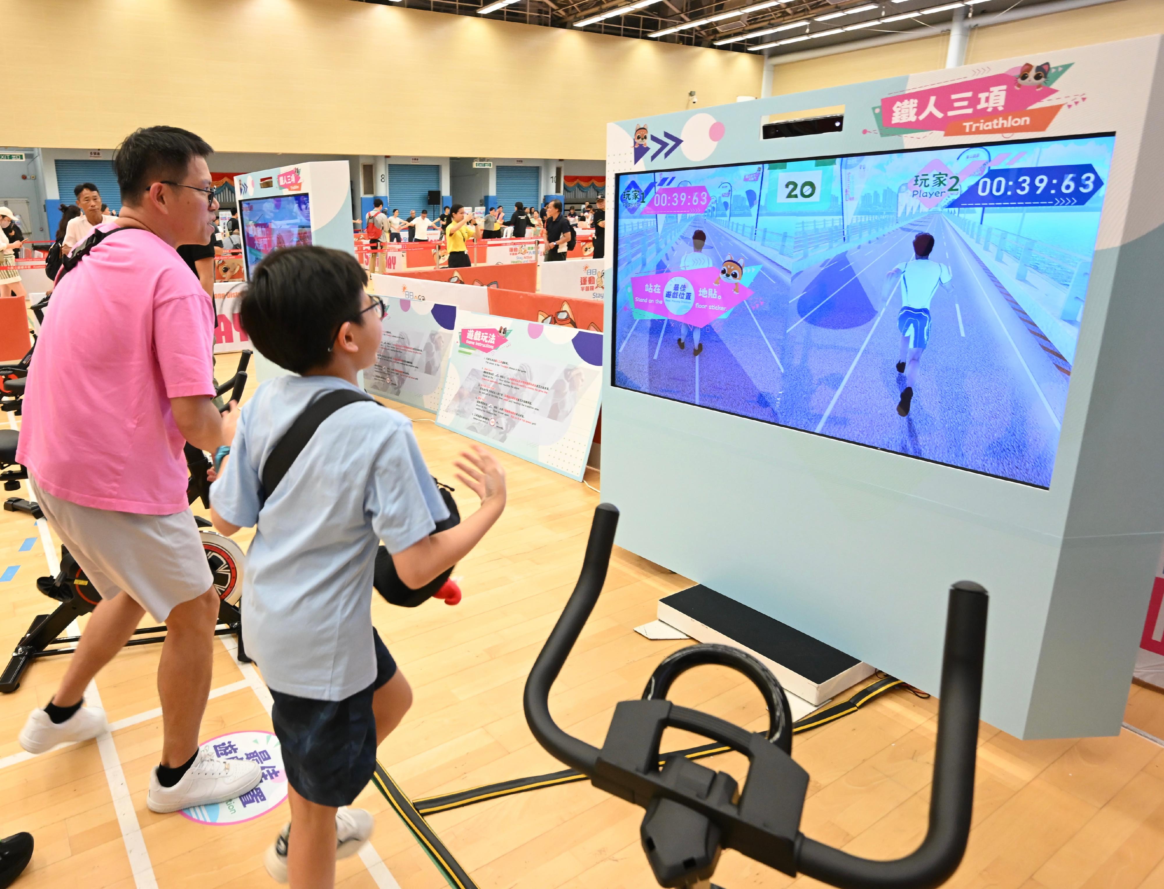 The Sport For All Day 2025 was held by the Leisure and Cultural Services Department today (August 3) with free recreation and sports programmes at designated sports centres in 18 districts for the public to join. Photo shows members of the public taking part in the virtual triathlon game.
