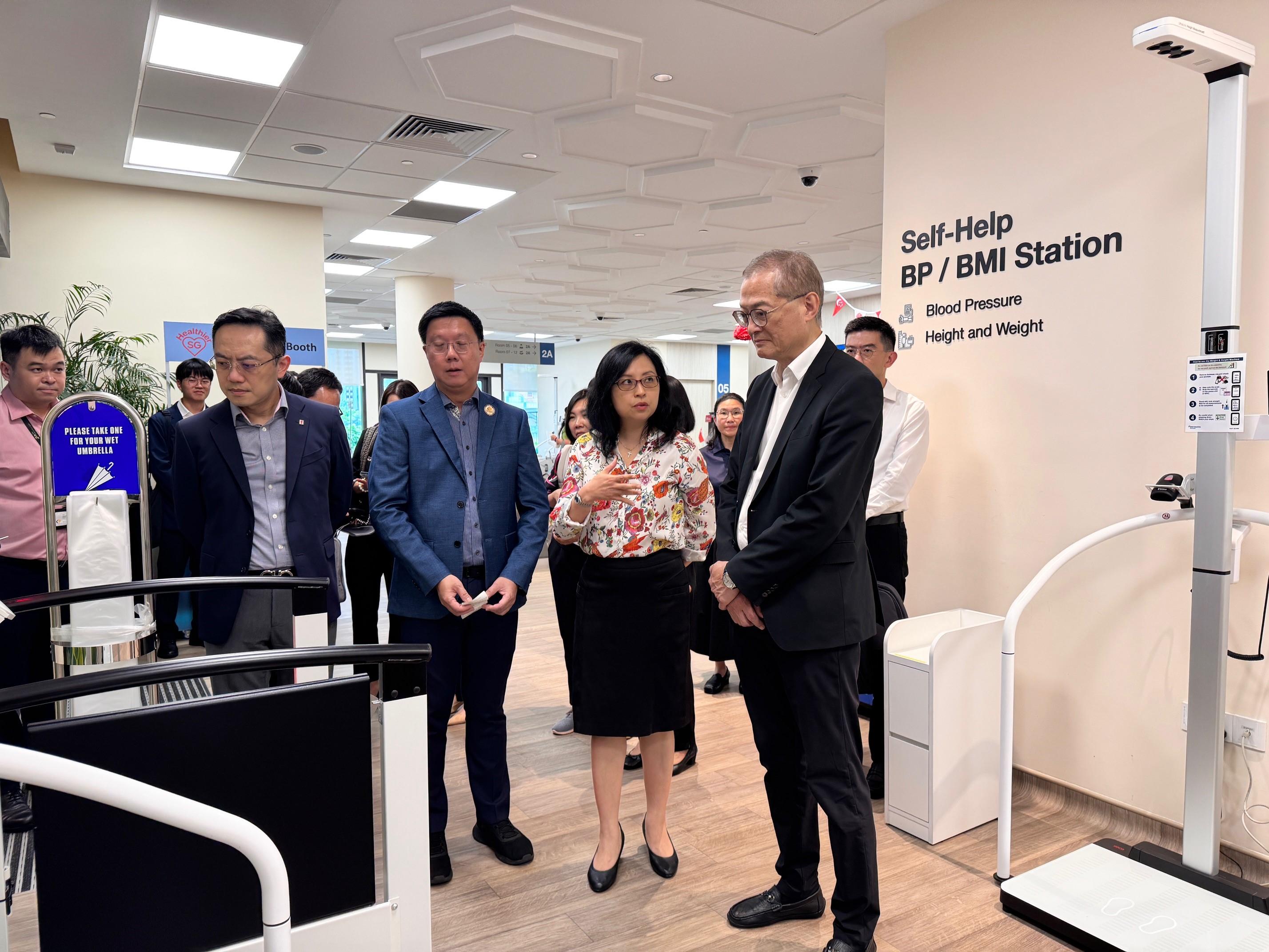 The Secretary for Health, Professor Lo Chung-mau (front row, first right), and the Director of Health, Dr Ronald Lam (front row, first left), visit the National Healthcare Group Sembawang Polyclinic in Singapore today (August 14).

