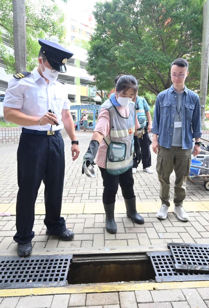 The Food and Environmental Hygiene Department (FEHD) conducted mosquito prevention and control work in Tuen Mun today (August 15). Photo shows FEHD staff instructing the Housing Department's outsourced cleaning worker to apply temephos sand granules.