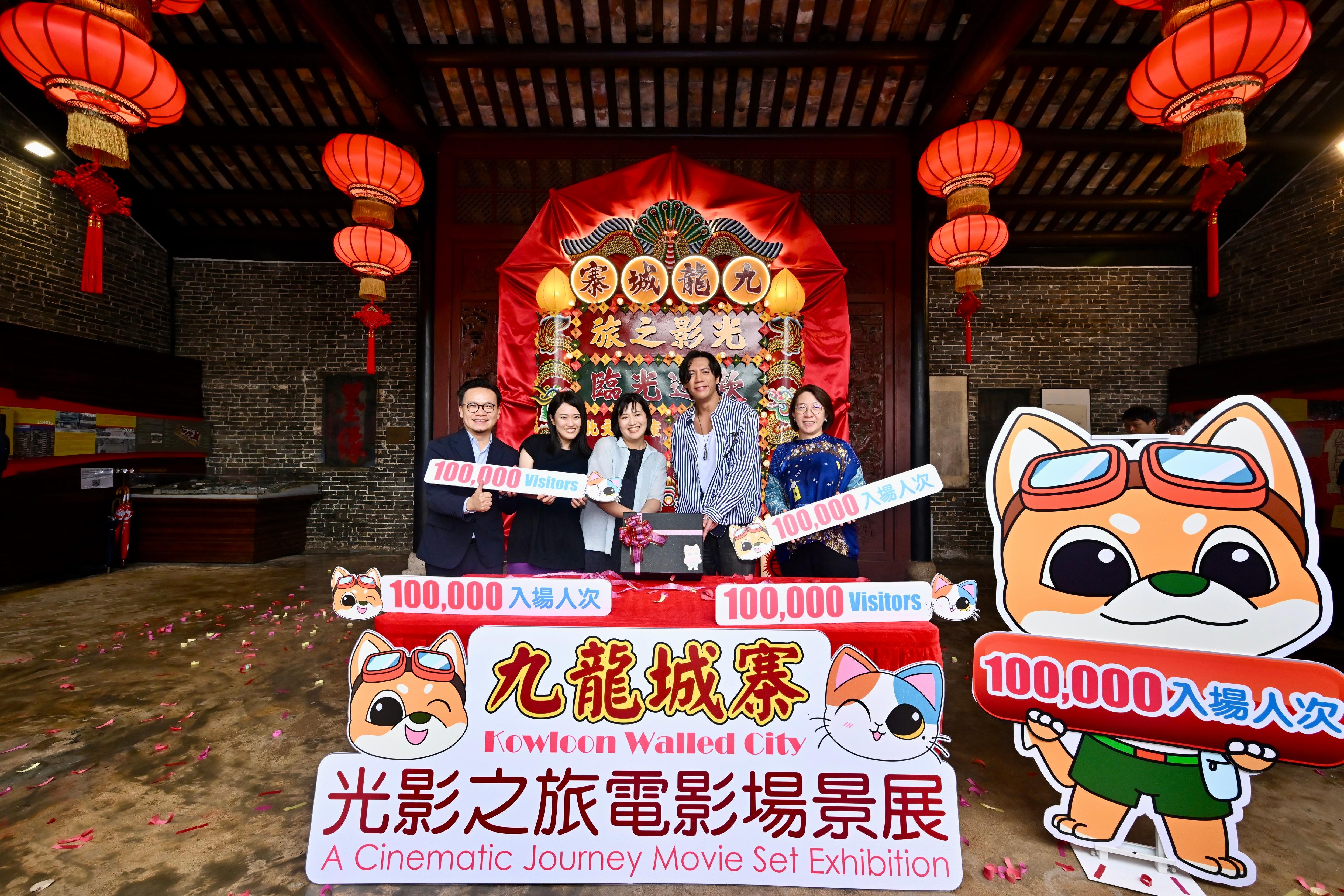 由文化體育及旅遊局轄下文創產業發展處策劃、電影發展基金資助的「九龍城寨光影之旅」電影場景展今日（八月十八日）迎來第十萬名參觀者。圖示康樂及文化事務署助理署長（康樂事務）馮妙玲（右一）、文創產業助理專員兼香港電影發展局秘書長麥聖希（左一）和《九龍城寨之圍城》演員張文傑（右二），向第十萬名參觀者（中）送上紀念品。