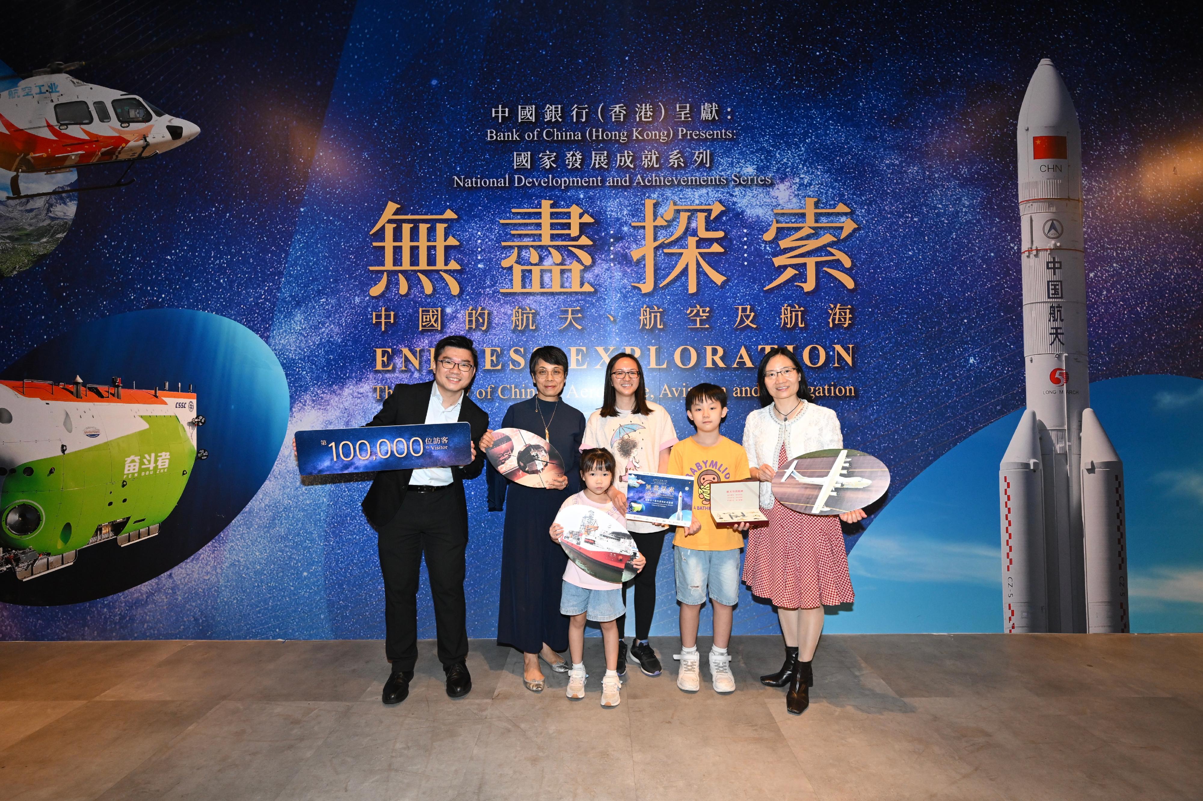 The "Bank of China (Hong Kong) Presents: National Development and Achievements Series - Endless Exploration: The Journey of Chinese Aerospace, Aviation and Navigation" exhibition, currently being held at the Hong Kong Science Museum (HKScM), welcomed its 100 000th visitor today (August 19). Photo shows the Acting Director of Leisure and Cultural Services, Miss Eve Tam (second left); the Deputy General Manager of Corporate Social Responsibility Office of Bank of China (Hong Kong), Ms Angel Yip (first right); and the Museum Director of the HKScM, Mr Patrick Lau (first left), welcoming the 100 000th visitor of the exhibition and presenting a gift to him.