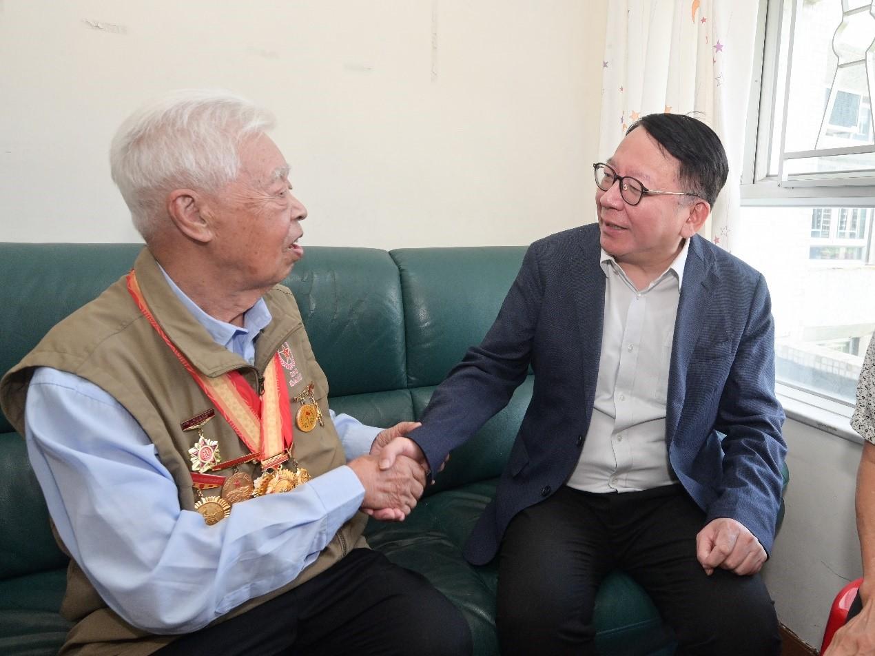 今年是中國人民抗日戰爭暨世界反法西斯戰爭勝利80周年，政務司司長陳國基和民政及青年事務局（民青局）局長麥美娟今日（八月二十九日）分別與中央人民政府駐香港特別行政區聯絡辦公室（中聯辦）副主任劉光源和中聯辦秘書長王松苗，上門探訪三位在港並曾參加抗戰的老兵，向他們表達慰問和關懷。圖示陳國基（右）與老兵交談。