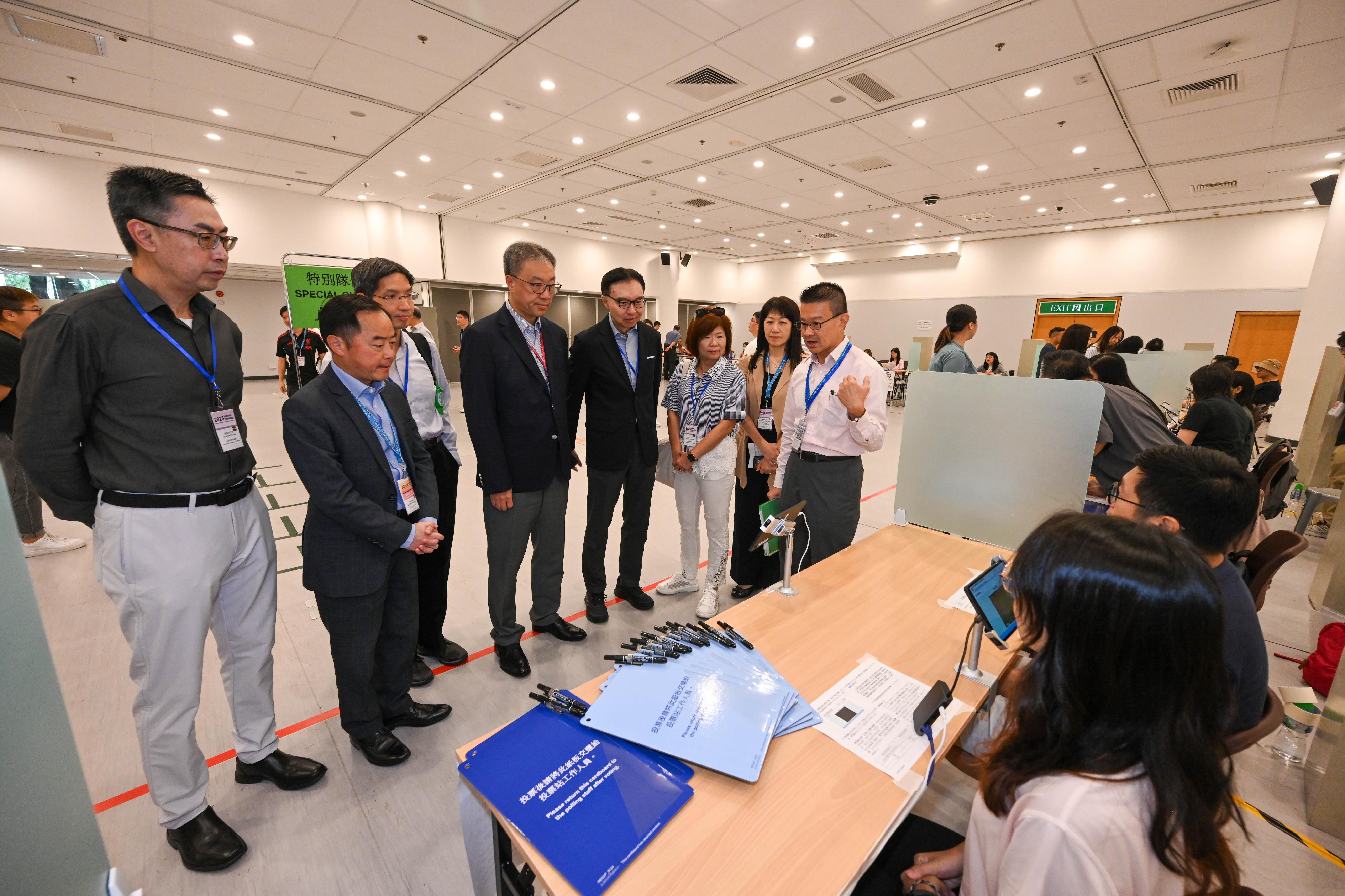 The Chairman of the Electoral Affairs Commission, Mr Justice David Lok (fourth left), accompanied by the Commissioner for Digital Policy, Mr Tony Wong (second left); the Convenor of the Technical Advisory Committee (TAC), Mr Sunny Lee (fourth right); Members of the TAC Mr Wilson Wong (first left), Ms Susanna Shen (third right), Mr Raymond Wong (third left); and the Chief Electoral Officer of the Registration and Electoral Office, Ms Natalie Chan (second right), visits the polling station of the 2025 Election Committee Subsector By-elections located at the Exhibition Gallery of Hong Kong Central Library this morning (September 6) to inspect the preparatory work. They are briefed by a polling staff member.