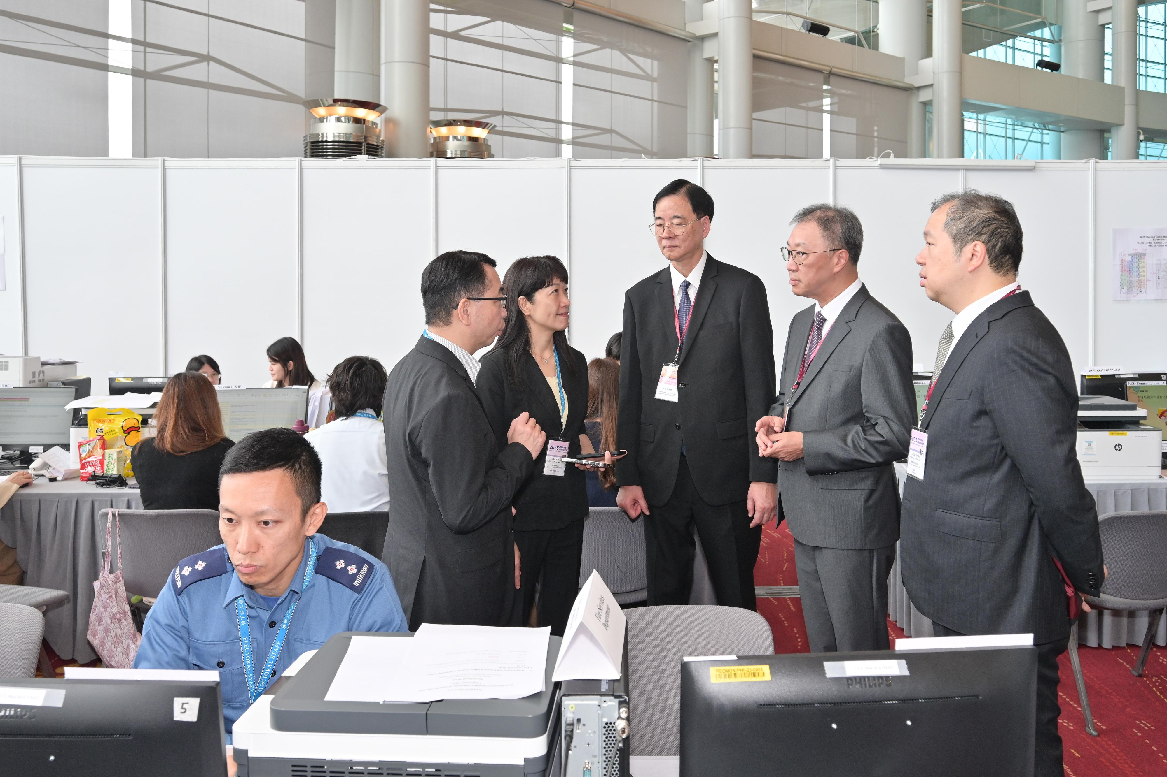 選舉管理委員會主席陸啟康法官（後排右二）、委員石丹理教授（後排中）和文本立資深大律師（後排右一）在選舉事務處總選舉事務主任陳淑華（後排左二）和首席選舉事務主任（選舉）陳志成（後排左一）的陪同下，今日（九月七日）上午視察位於香港會議展覽中心的二○二五年選舉委員會界別分組補選中央指揮中心。