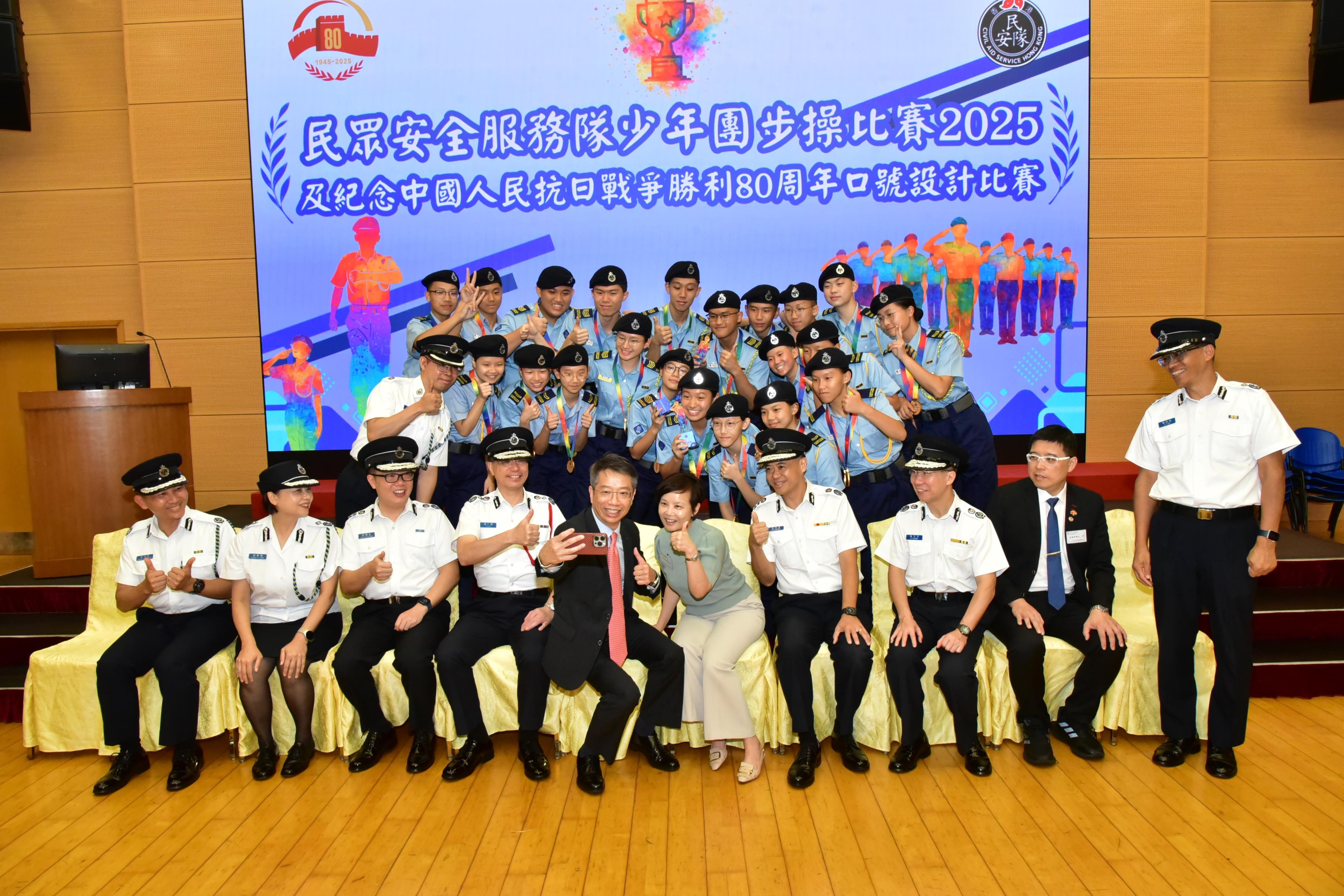 民眾安全服務隊（民安隊）少年團今日（九月七日）在民安隊總部舉行步操比賽2025及紀念中國人民抗日戰爭勝利80周年口號設計比賽。圖示公務員事務局常任秘書長梁卓文（左五）和民安隊長官與少年團成員合照。
