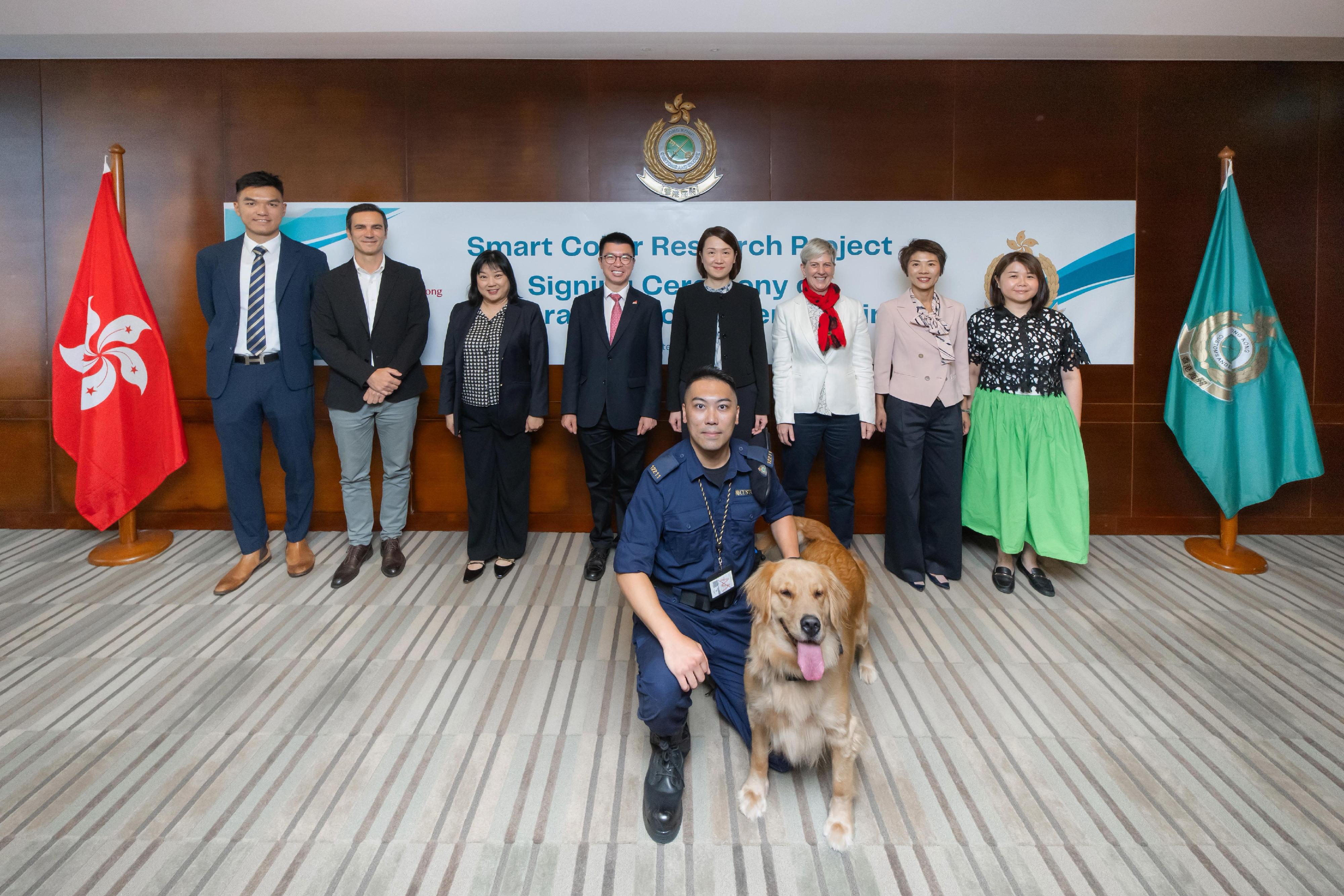 The Customs and Excise Department signed a Memorandum of Understanding to advance the operational effectiveness of Customs detector dogs through the Smart Collar Research Project with the City University of Hong Kong (CityU) today (September 11) at the Customs Headquarters Building. Photo shows the Assistant Commissioner (Boundary and Ports) of Customs and Excise, Ms Chiang Yi-lee (back row, fourth right), with other Customs officials and representatives of CityU.