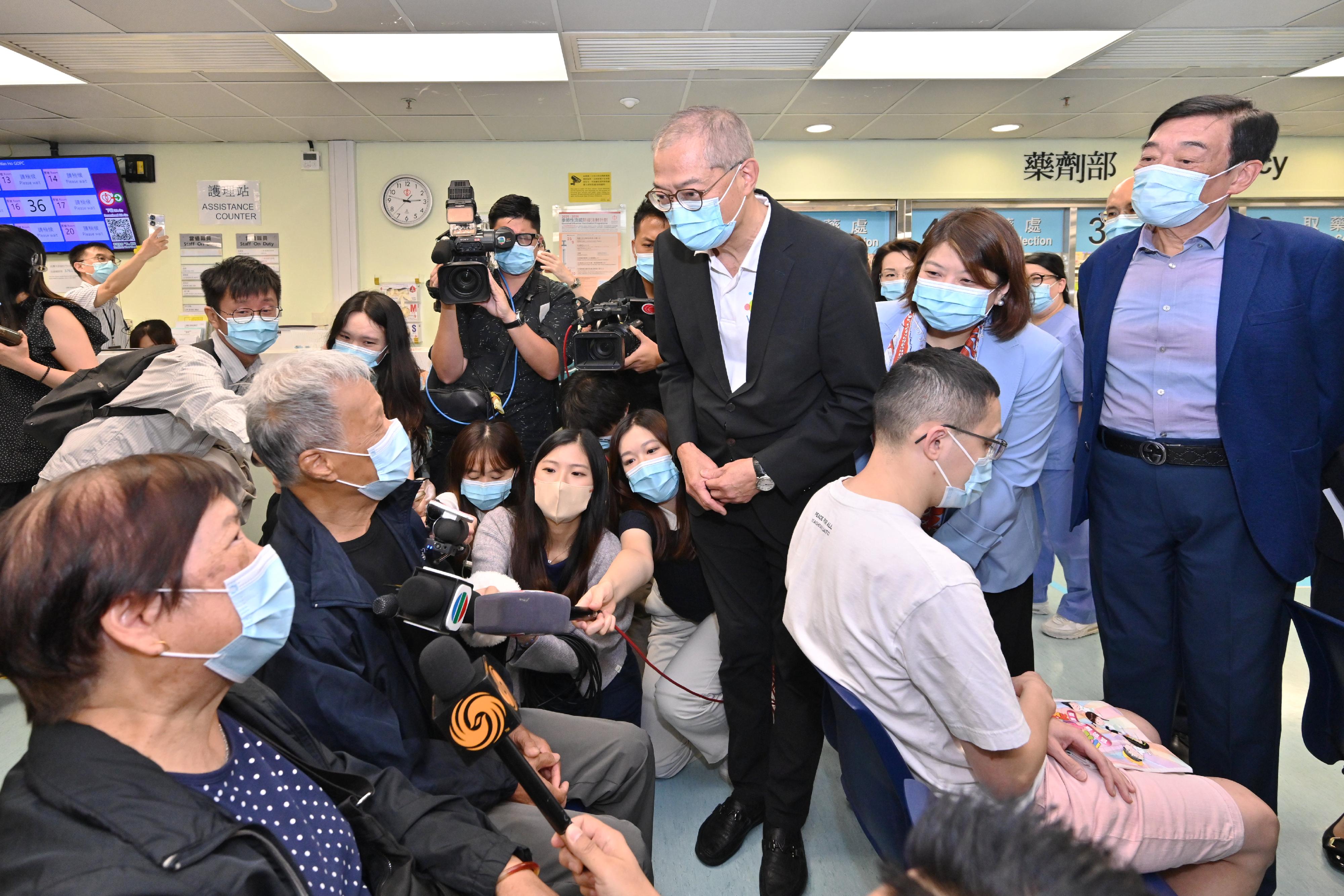 醫務衞生局局長盧寵茂教授（中）今日（九月十五日）在西灣河普通科門診診所接種季節性流感疫苗和新冠疫苗前與市民交流。醫院管理局（醫管局）主席范鴻齡（右一）和醫管局行政總裁李夏茵醫生（右二）亦有陪同。