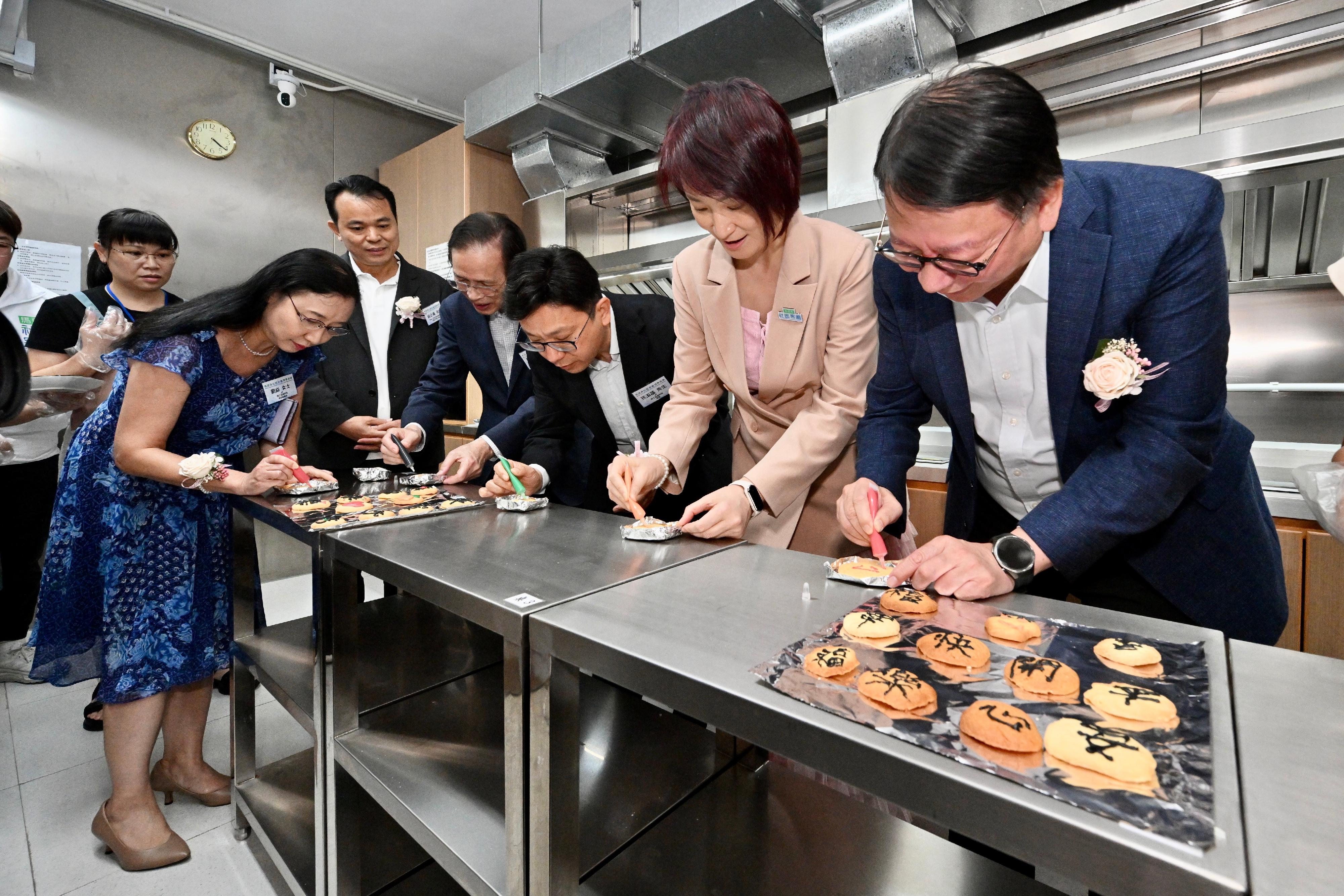 政務司司長陳國基今日（九月十五日）主持馬頭角社區客廳開幕典禮。勞工及福利局局長孫玉菡、中央人民政府駐香港特別行政區聯絡辦公室九龍工作部部長祝小東、嘉濤（香港）控股有限公司主席魏仕成、愛。聯繫慈善基金有限公司創會主席李慧琼博士、勞工及福利局常任秘書長劉焱、社會福利署署長杜永恒和愛。聯繫慈善基金有限公司董事簡志豪亦一同主禮。圖示陳國基（右一）和孫玉菡（右三）在共享煮食間與受惠家庭製作曲奇，並在曲奇上寫上祝福詞語。