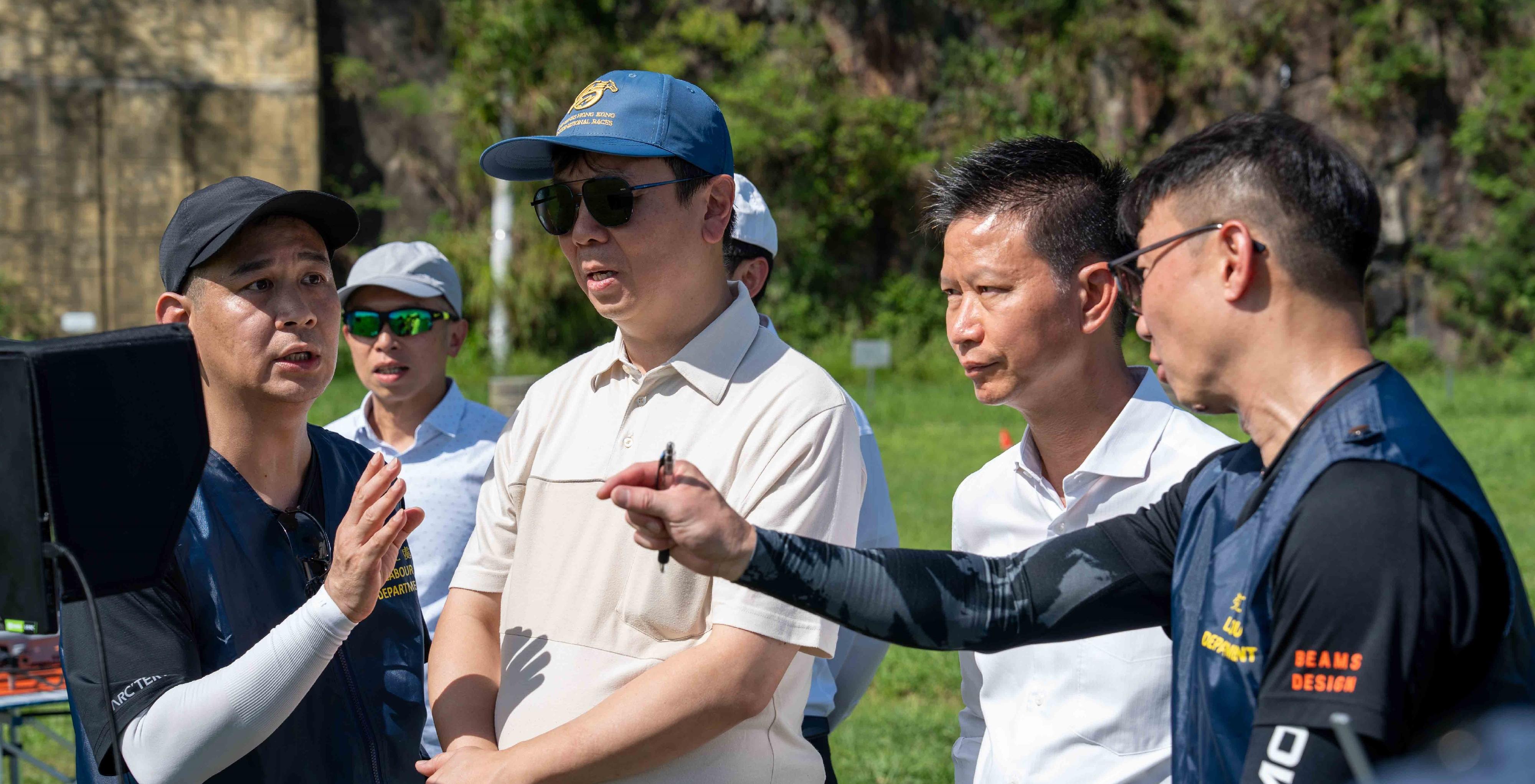 The Labour Department will start using small unmanned aircraft (SUA) from October to assist with inspections and enforcement actions. Photo shows the Commissioner for Labour, Mr Sam Hui (front row, second right), and the Deputy Commissioner for Labour (Occupational Safety and Health), Mr Vincent Fung (front row, second left), observing an SUA drill earlier.