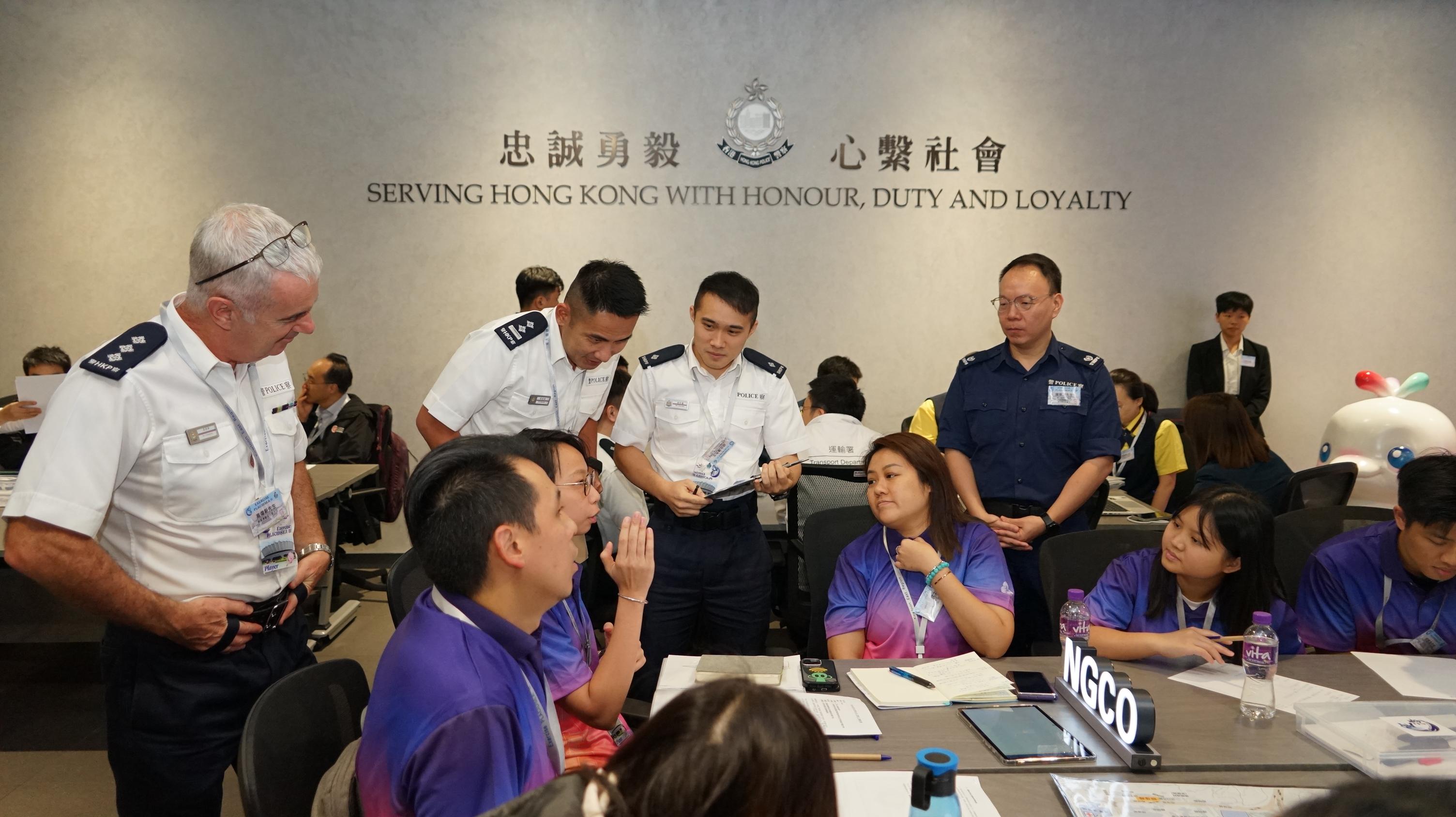 警務處東九龍總區今日（九月二十六日）在東九龍總部就第十五屆全國運動會（十五運會）和全國第十二屆殘疾人運動會暨第九屆特殊奧林匹克運動會（殘特奧會）舉行代號為「定海II」的跨部門桌上演練。圖示警方與政府部門及相關機構代表商討應對可能發生的突發情境所採取的措施。