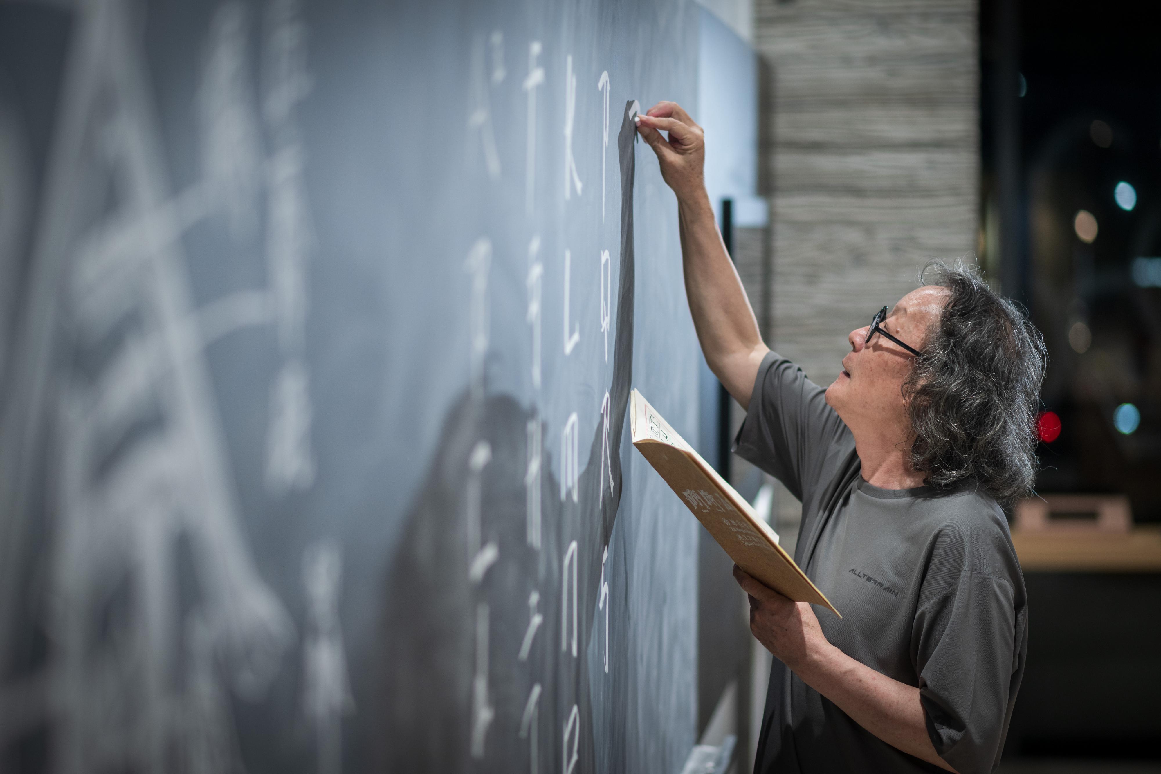 Oil Street Art Space is staging world-renowned artist Xu Bing's "Eying East, Wondering West - Square Word Calligraphy Classroom on the Move" exhibition from today (September 29) to January 11 next year. Photo shows Xu setting up the exhibition.