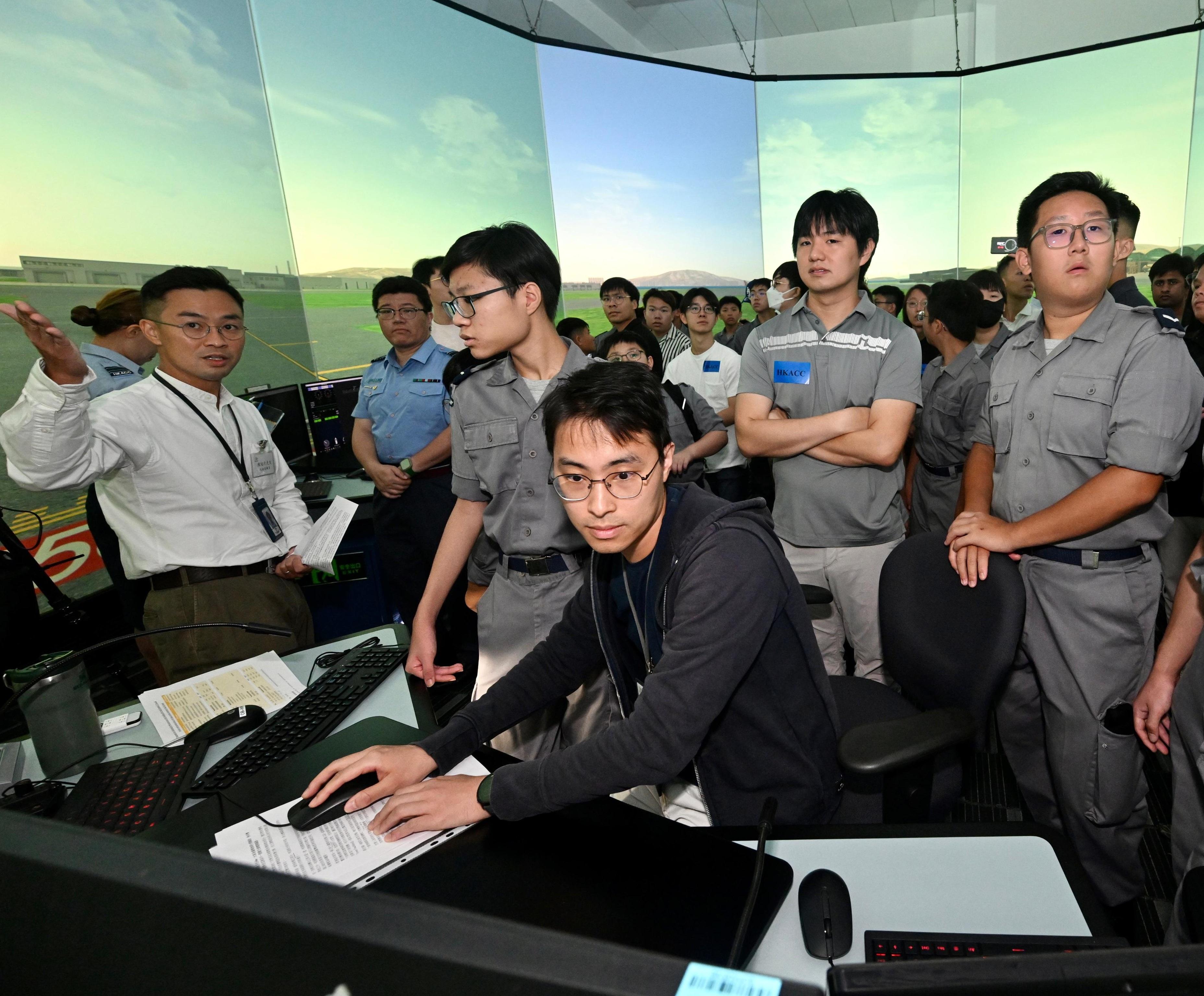 The Civil Aviation Department (CAD) today (October 4) held an aviation-themed youth activity to celebrate the 76th Anniversary of the founding of the People's Republic of China and commemorate a century of Kai Tak's legacy. Photo shows young people participating in the demonstration session of air traffic control tower simulator at the CAD headquarters.