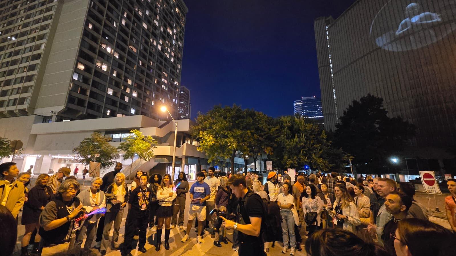 多倫多「白晝之夜」藝術展二○二五展出由香港媒體藝術家飽藹倫創作、加拿大策展人劉雪鈴創作的跨文化藝術作品《明明目》。圖示參觀者體驗投影藝術裝置《明明目》帶來的不同視角。