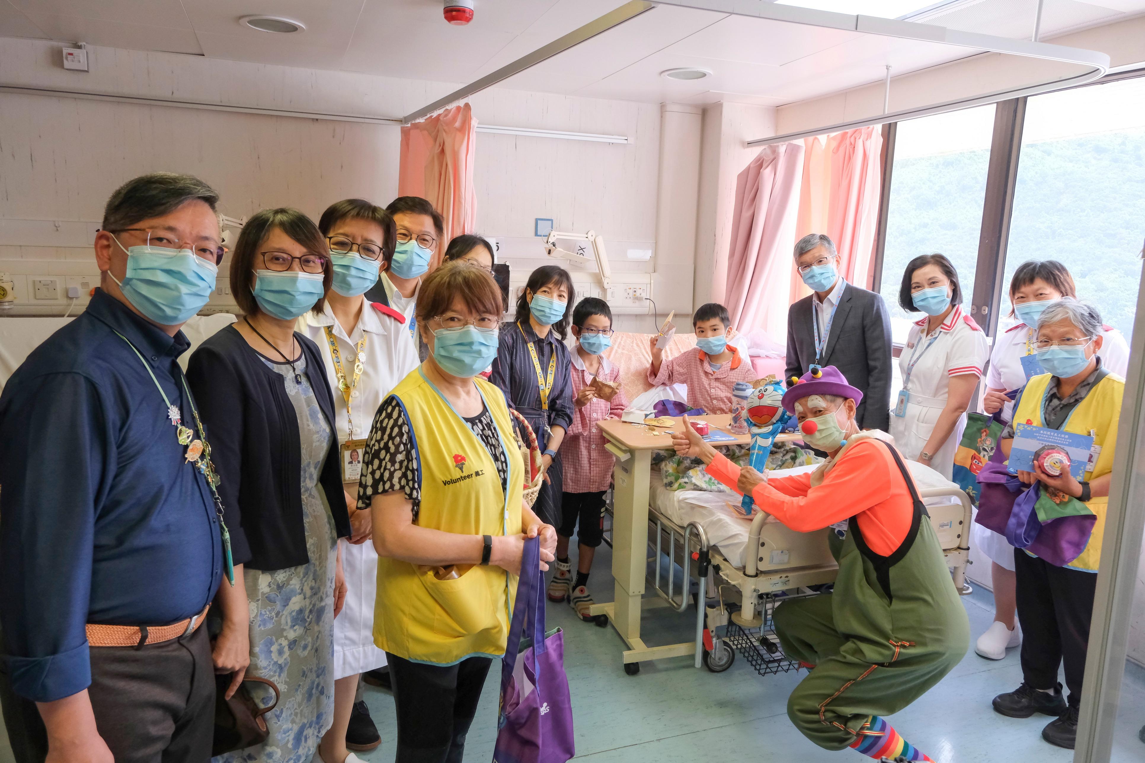 The Cluster Chief Executive of the New Territories East Cluster, Dr Simon Tang (back row, fourth right), joined volunteers and colleagues in visiting the paediatric ward. They delivered handmade red bean and purple sweet potato mooncakes, special gift packs, and mooncake-shaped towels to young patients, bringing them the joy and warmth of the Mid-Autumn Festival.
