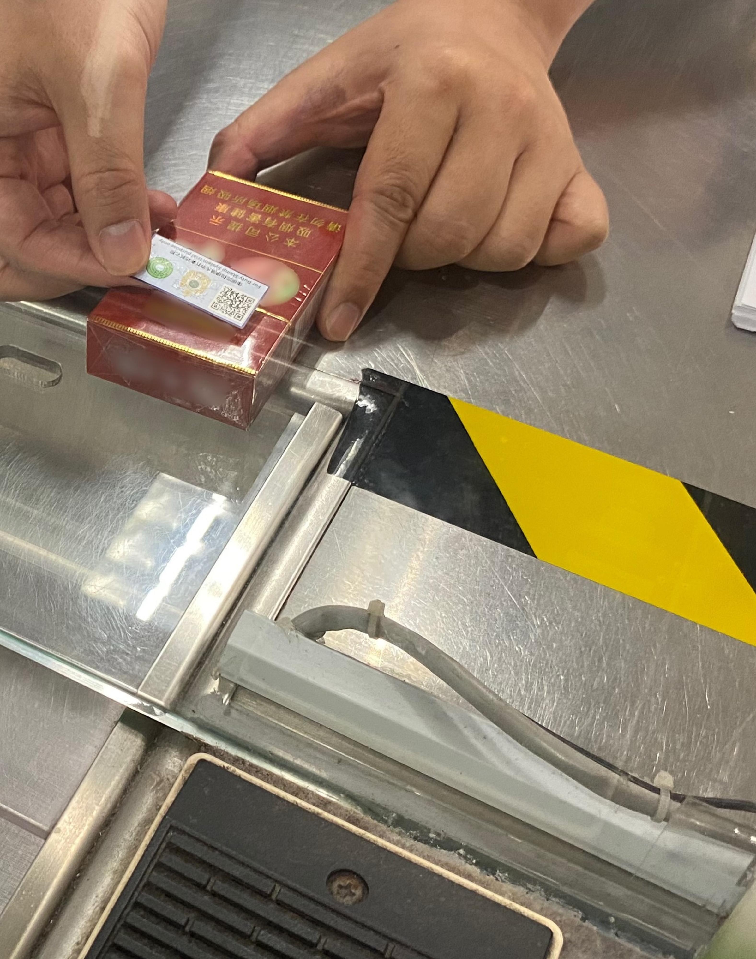 Hong Kong Customs launched a three-month pilot run for the duty stamp system on October 6. Photo shows Customs officer affixing a trial duty stamp to a cigarette package.
