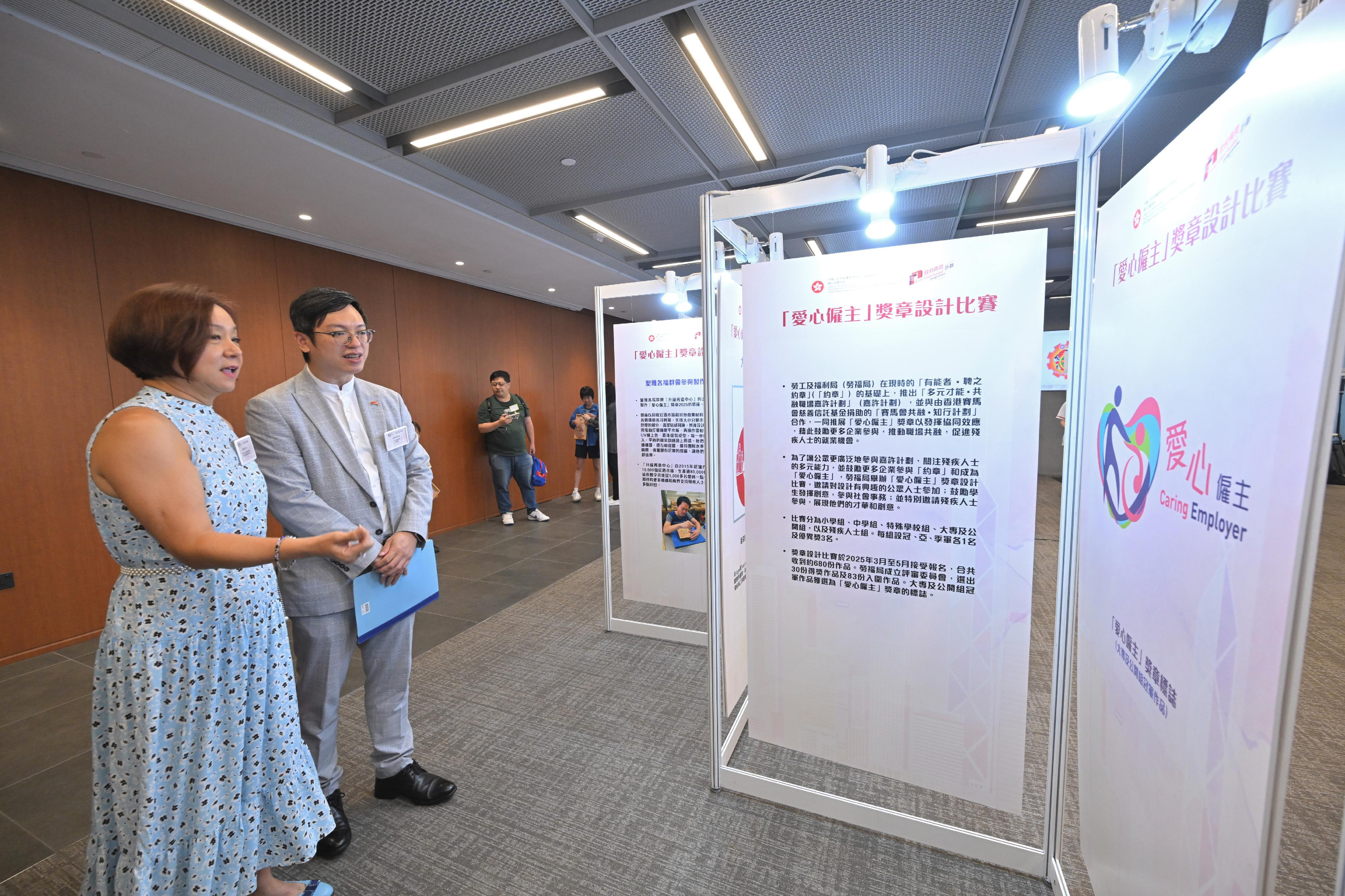 勞工及福利局（勞福局）今日（十月十日）舉辦「愛心僱主」獎章2025頒獎典禮。圖示勞福局副局長何啟明（左二）參觀「愛心僱主」獎章設計比賽得奬作品展覽。