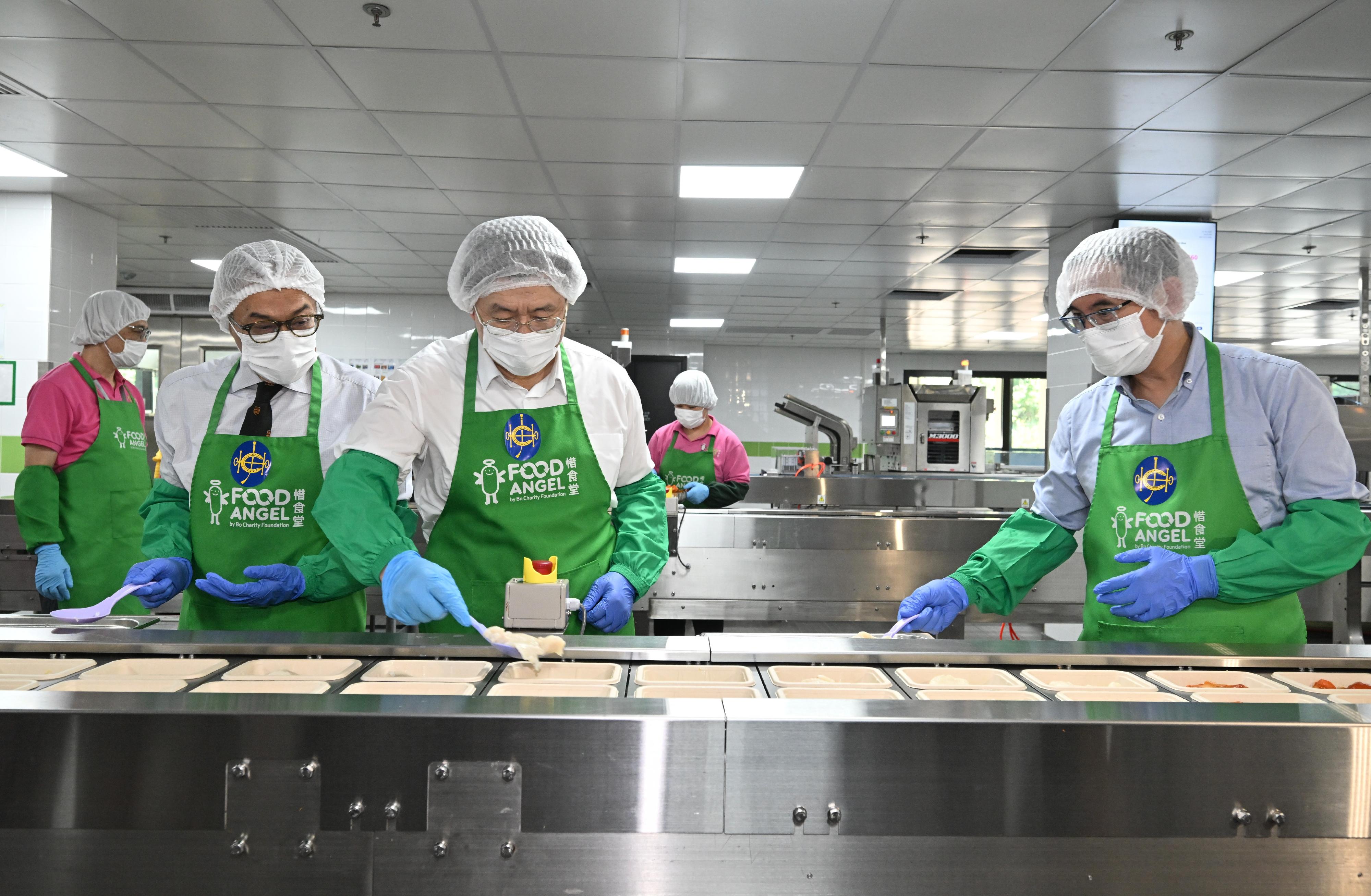 政務司副司長卓永興（中）今日（十月十五日）出席惜食堂賽馬會食品製作中心開幕典禮後參觀食品製作中心，並參與製作飯餐。旁為香港賽馬會董事胡家驃（左）和發展局副局長林智文（右）。

