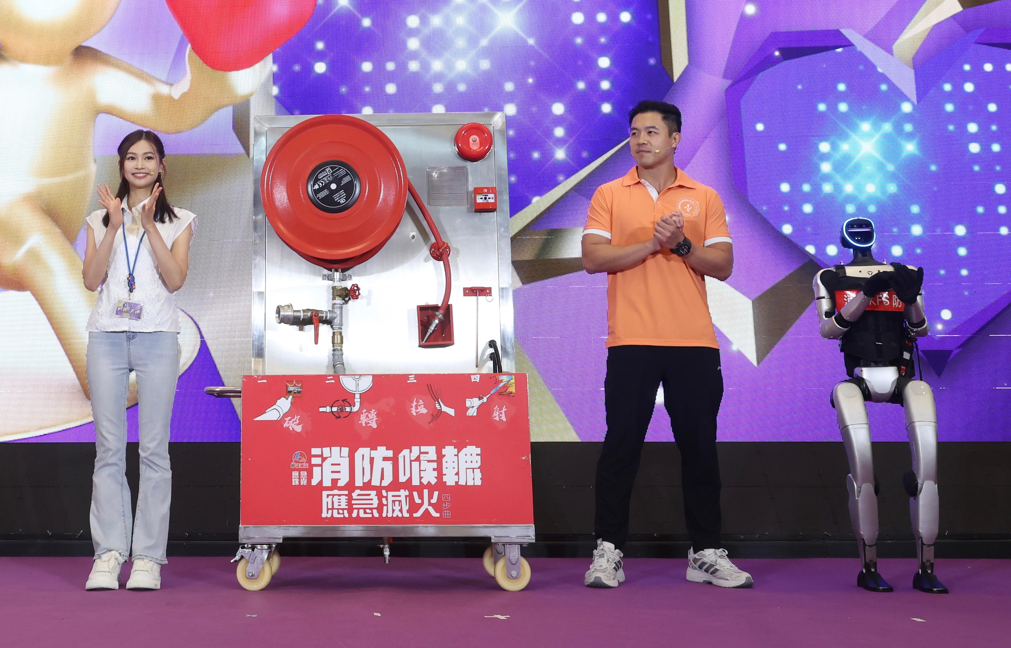 The Fire Services Department (FSD) held the Save Lives x Emergency Response Ceremony cum Carnival today (October 18), with artiste Rosita Kwok serving as the Big Heart Ambassador. Photo shows Kwok (left), and a trainer of the FSD Community Emergency Responder Scheme (right), sharing tips for emergency preparedness with the public, together with a robot that makes its first appearance.