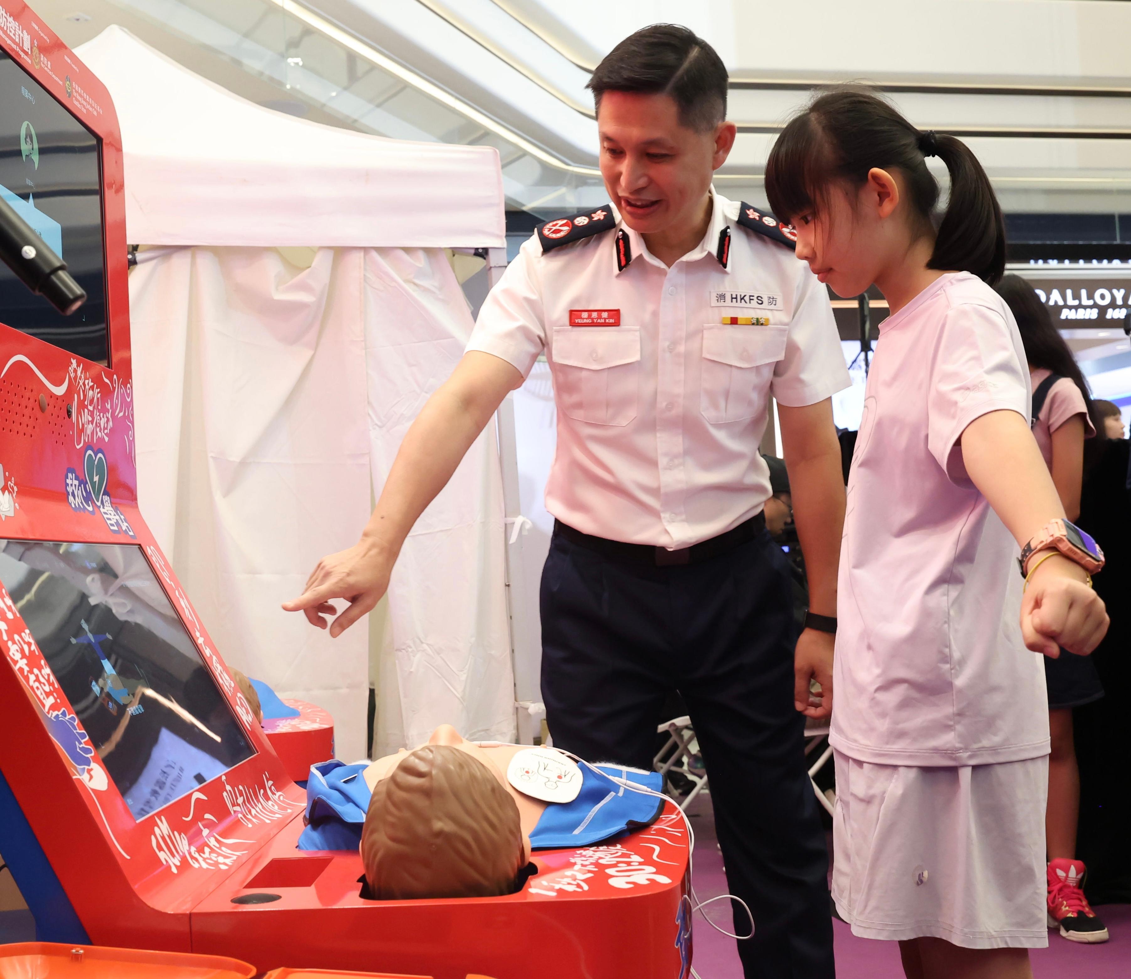 The Fire Services Department held the Save Lives x Emergency Response Ceremony cum Carnival today (October 18). Photo shows the Director of Fire Services, Mr Andy Yeung (left), chatting with a member of the public learning to perform cardiopulmonary resuscitation (CPR) and to use an automated external defibrillator (AED) at a CPR & AED Self-learning Kiosk.
